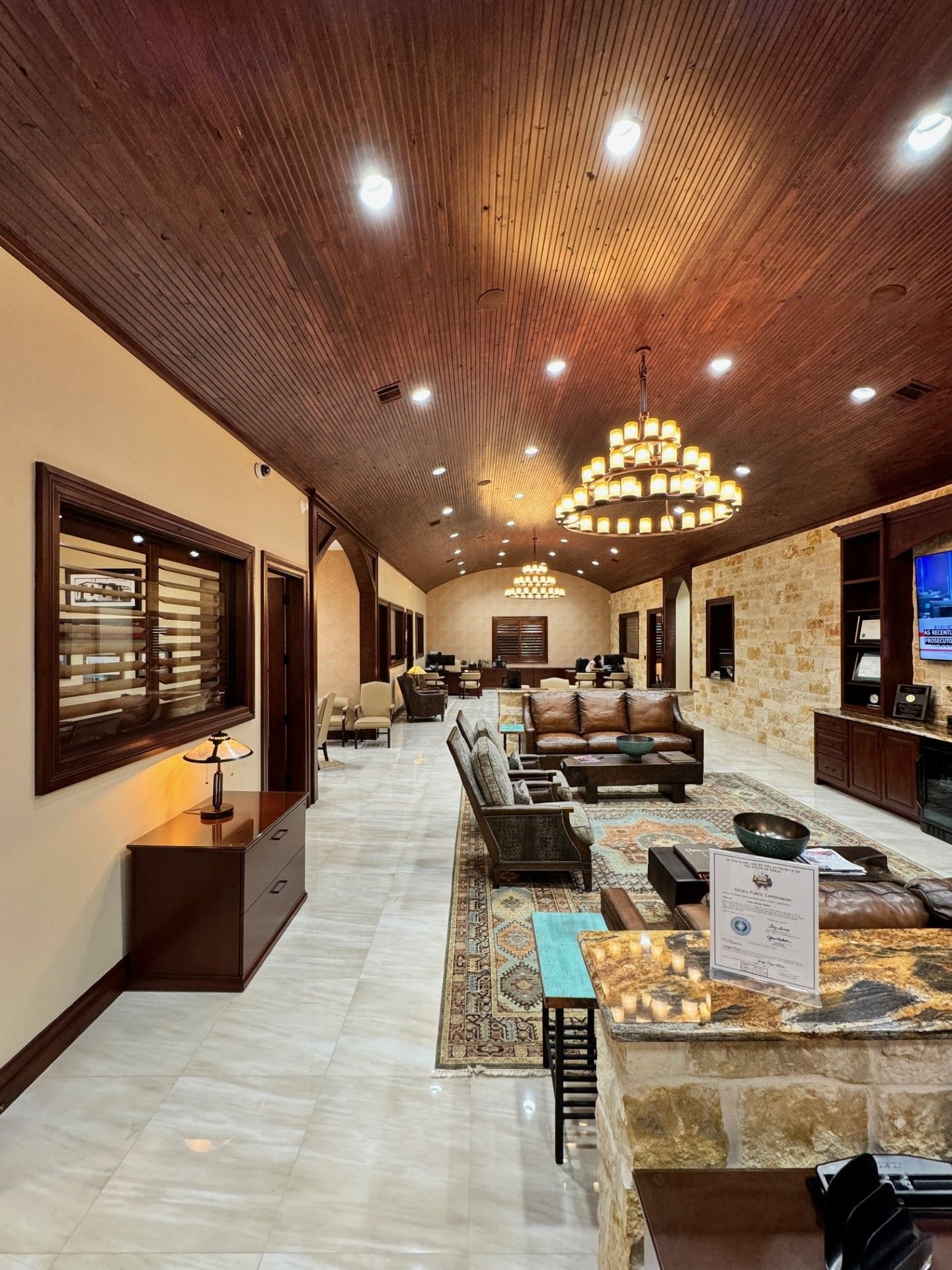 Elegant living room with chandelier, curved wood ceiling, and neutral sofas around a marble coffee table