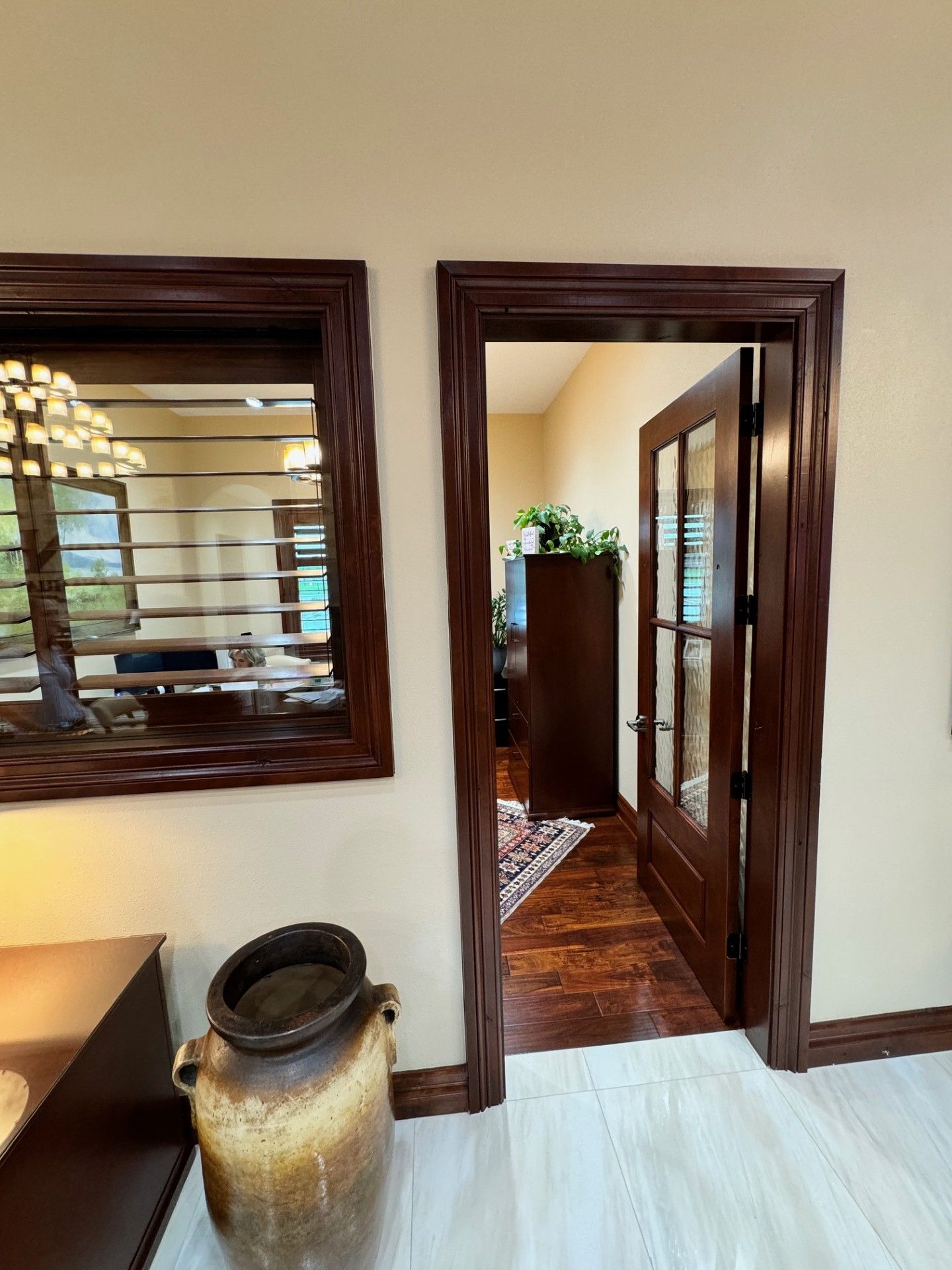 Hallway with wood-trimmed doorway, window shutters, and a large ceramic vase in the foreground
