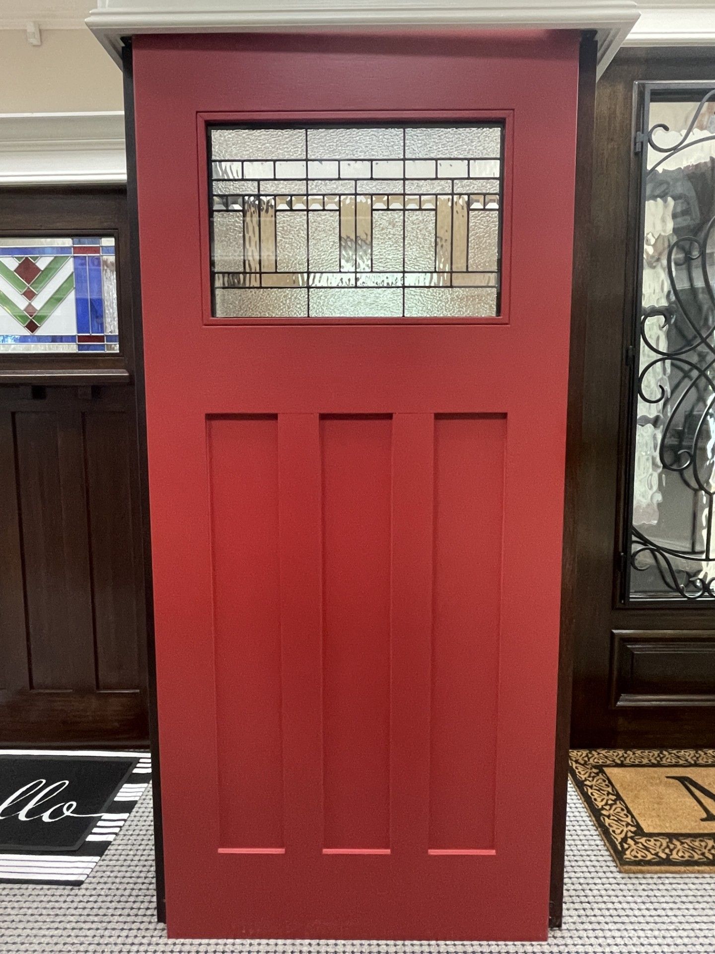 Red front door with small stained-glass window in a storefront interior
