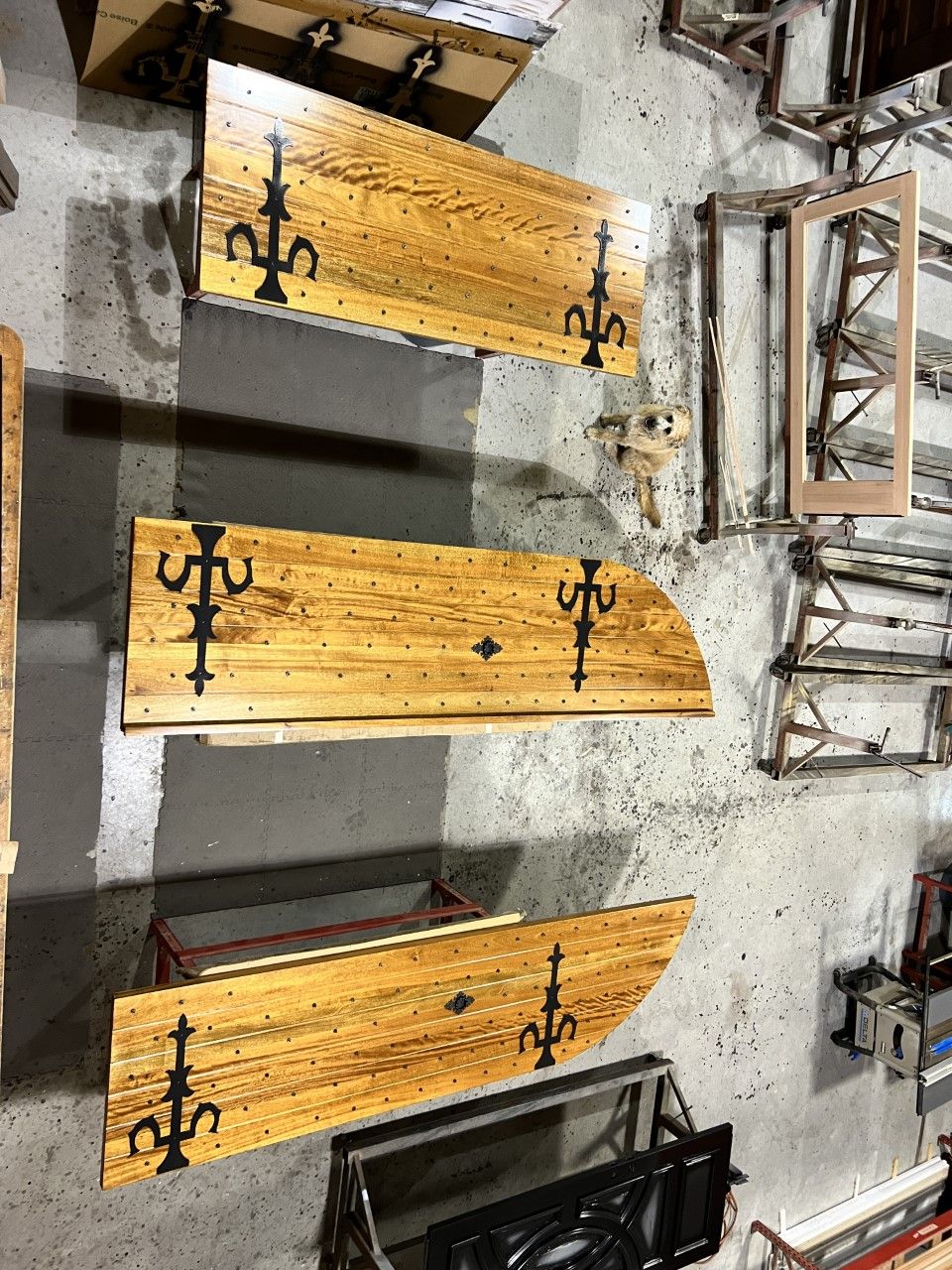 Rustic wooden church pews with black metal brackets arranged in a workshop or showroom