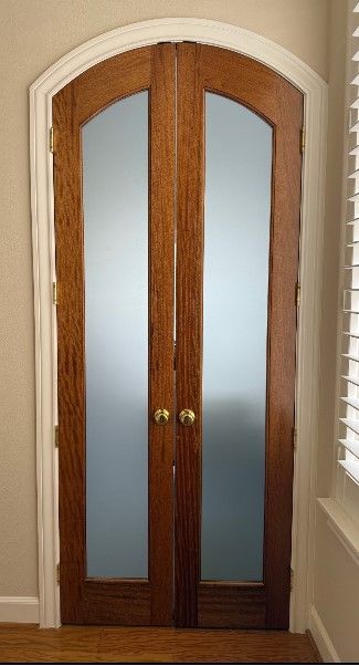 Wooden double French doors with frosted glass panels in a hallway beside white blinds.