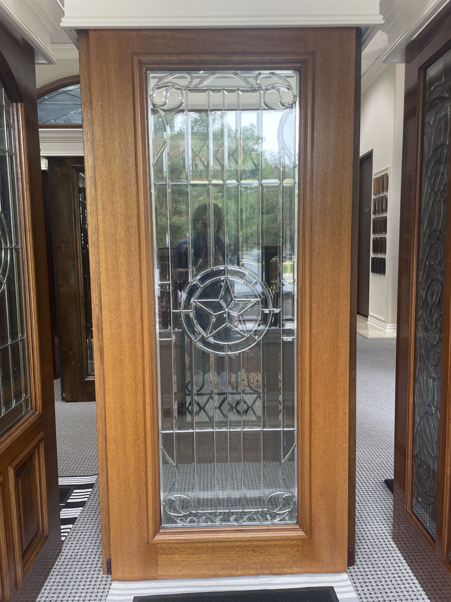Wooden front door with decorative frosted glass panel and circular design, viewed in a hallway