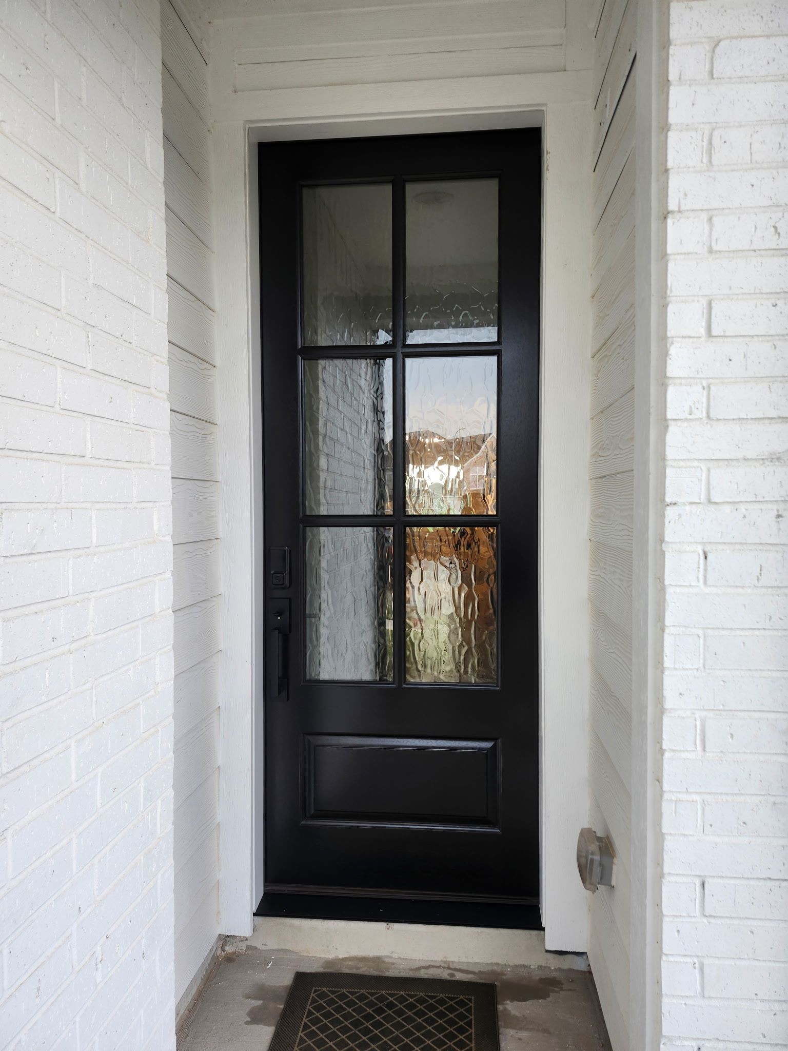 Black front door in a white-painted entryway with frosted glass panes