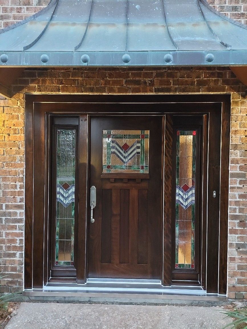 Front door with wood panels and stained-glass sidelights set in a brick entryway
