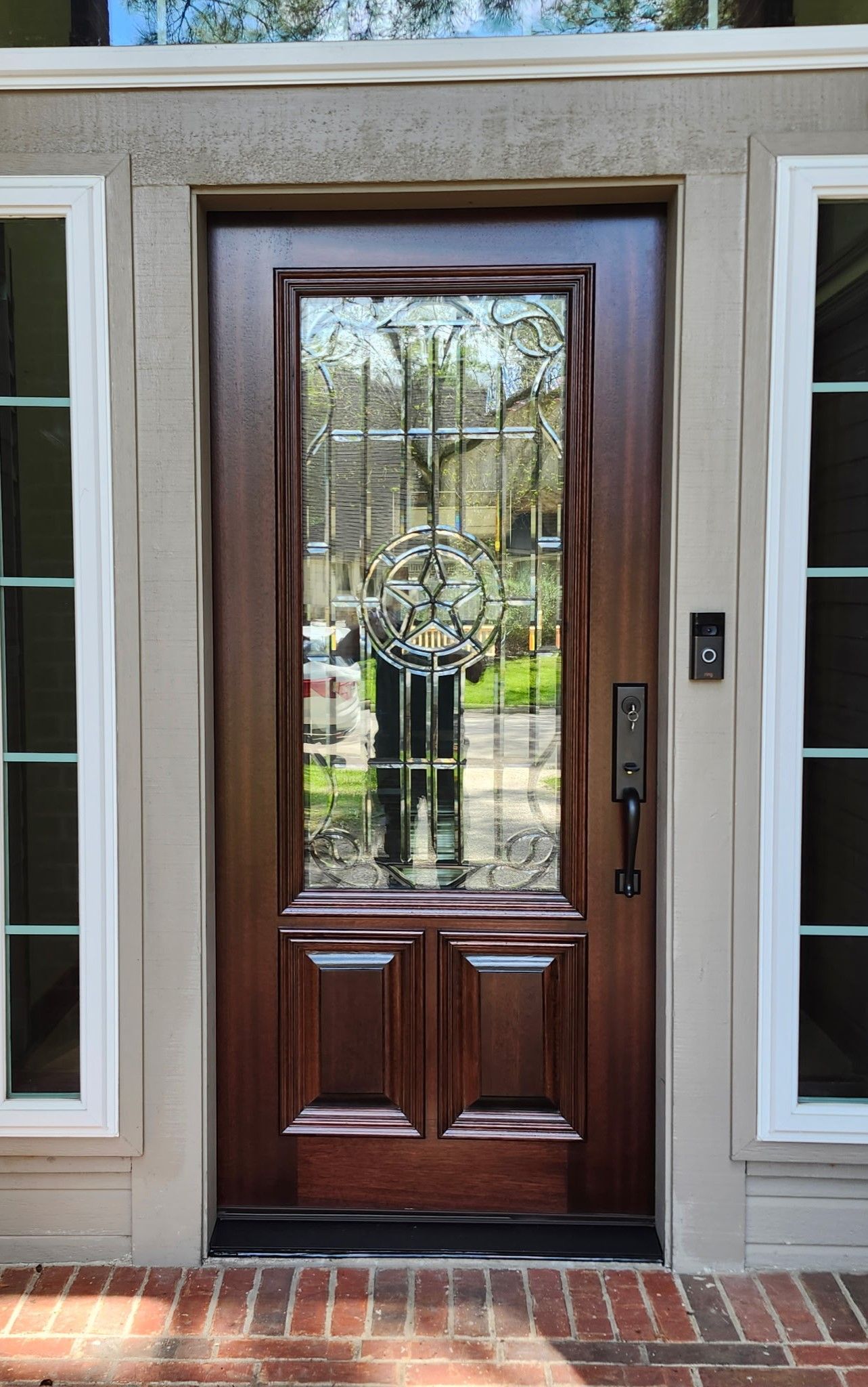 Front entrance with a dark wood door and glass panel, flanked by narrow windows and a brick step.