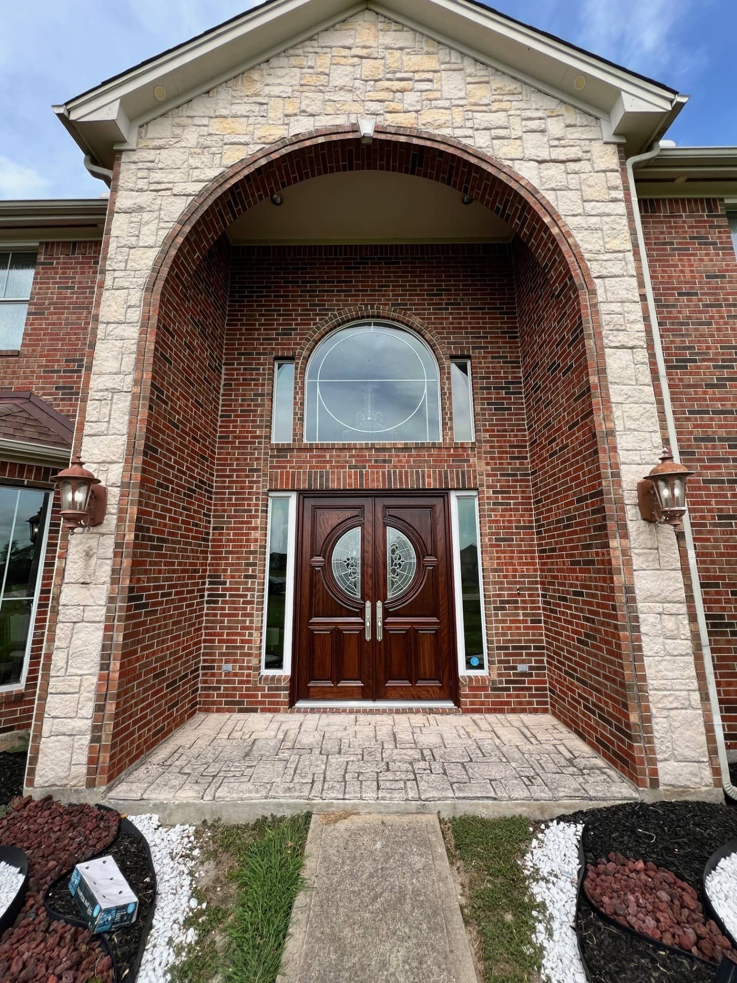 Brick townhouse entrance with arched stone portico, double wooden doors, and a small walkway.