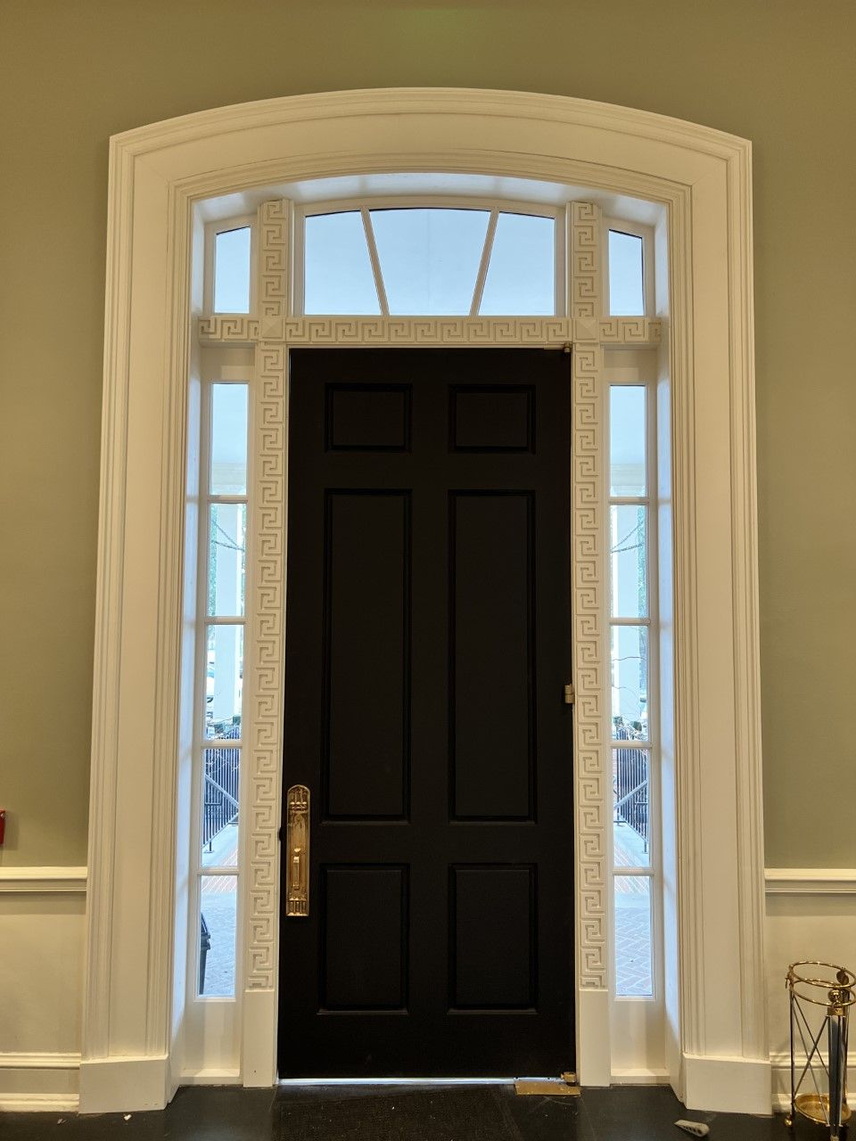 Black front door with sidelights and arched window in a light-colored entryway