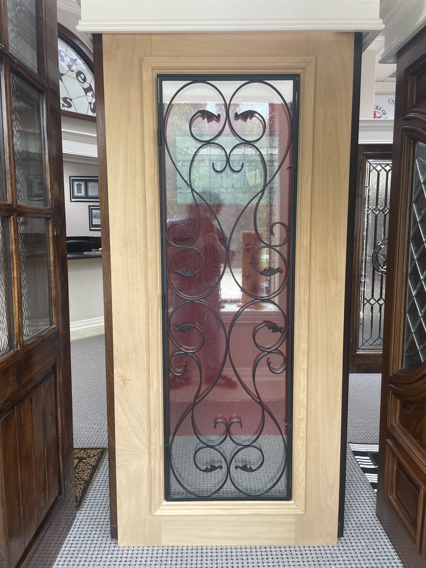 Decorative wrought-iron window inset in a light wood frame, flanked by dark wood panels.
