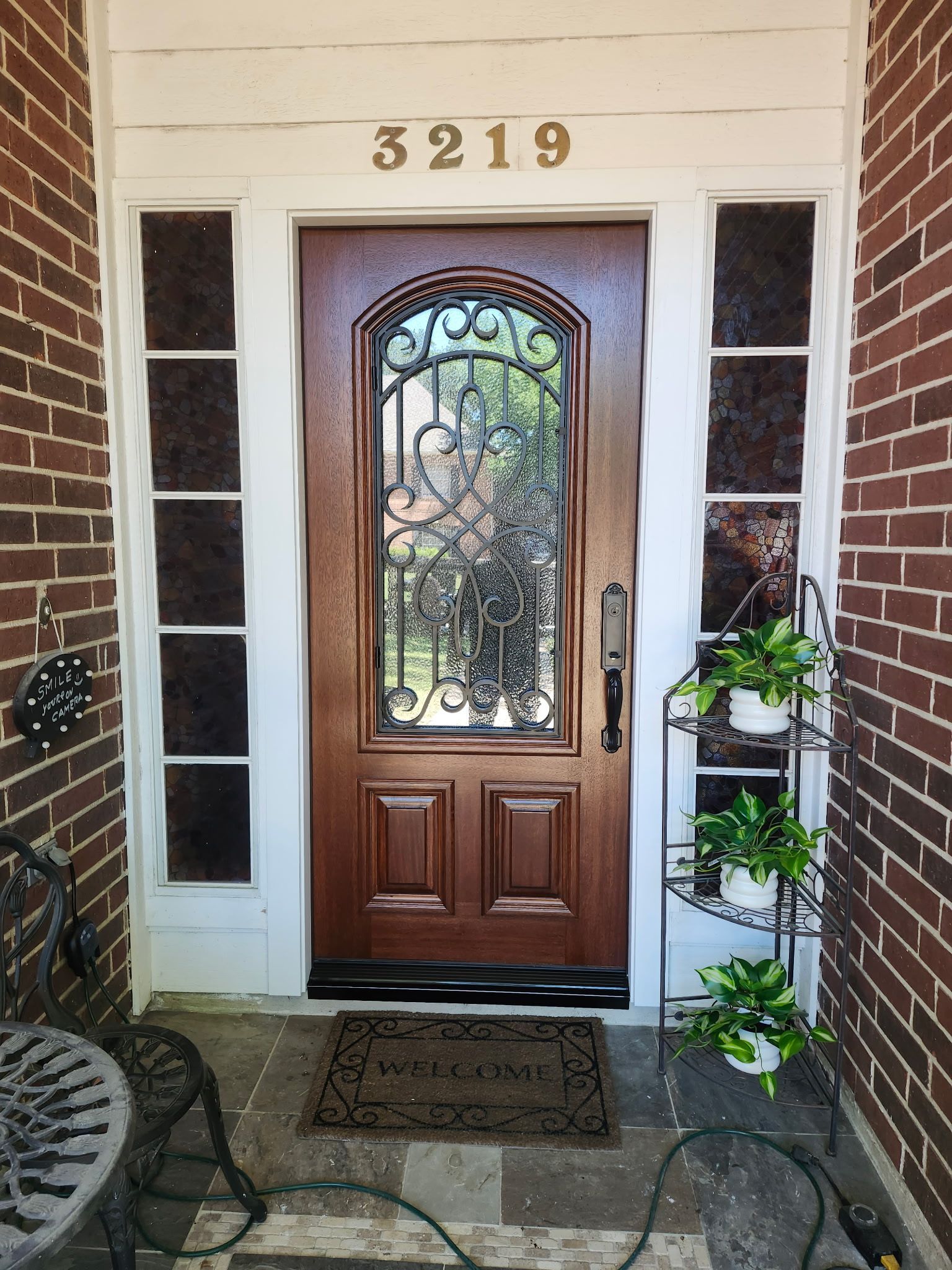 Front porch with a wooden front door, house number 3219, potted plants, and a welcome mat.