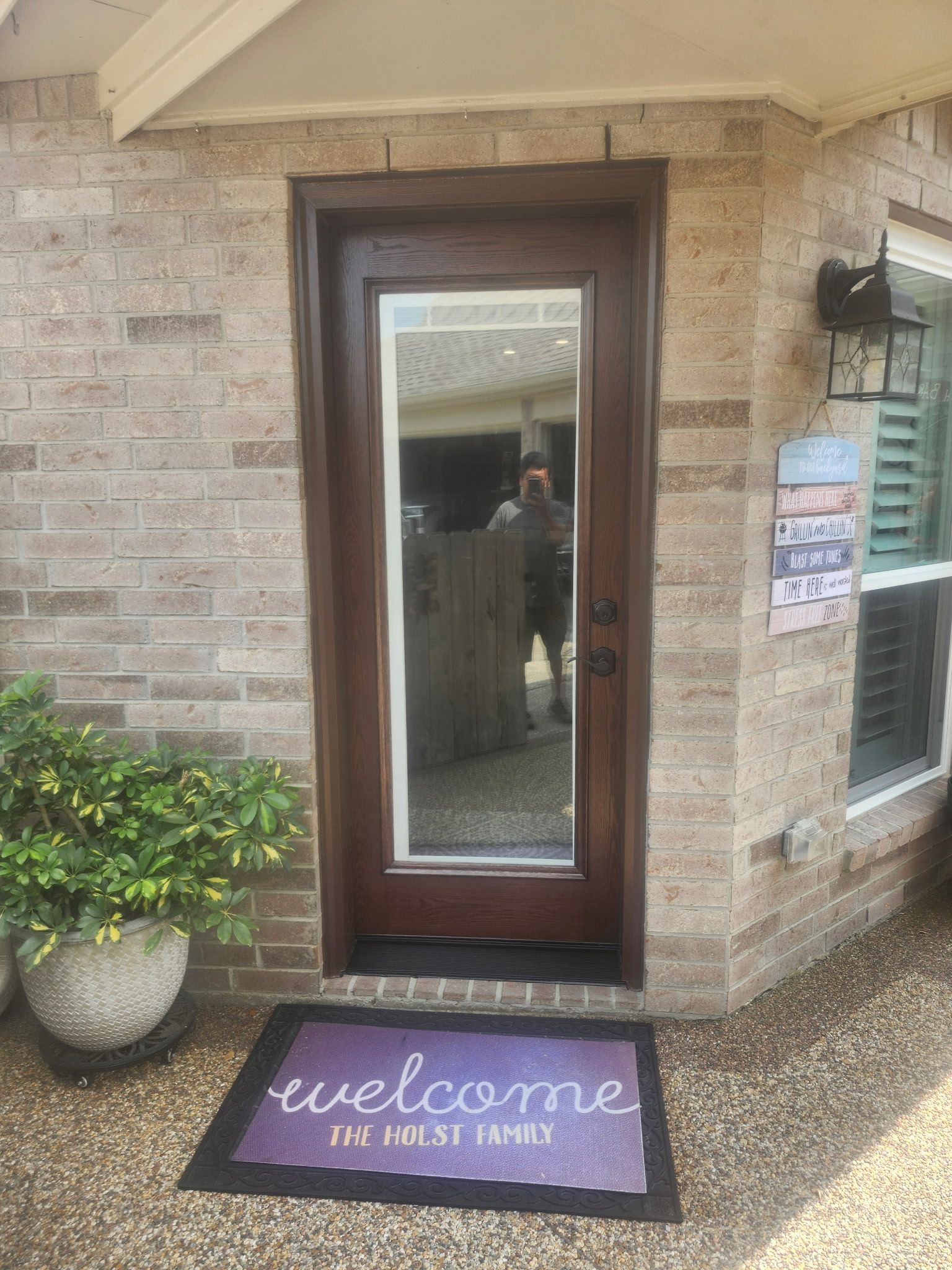 Front door with glass panel and “welcome” mat at a brick house entrance