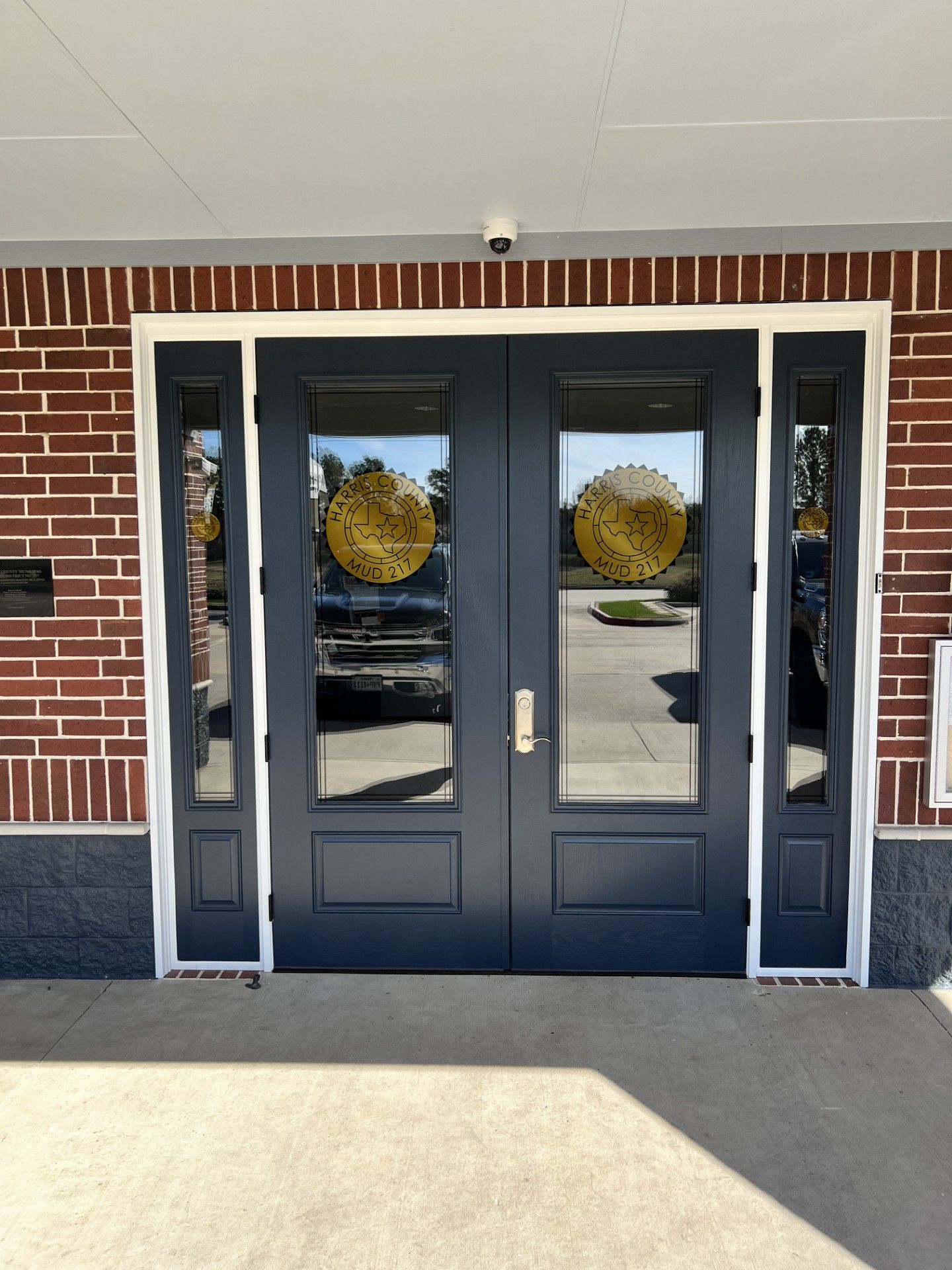 Dark double glass doors with white trim on a brick building entrance