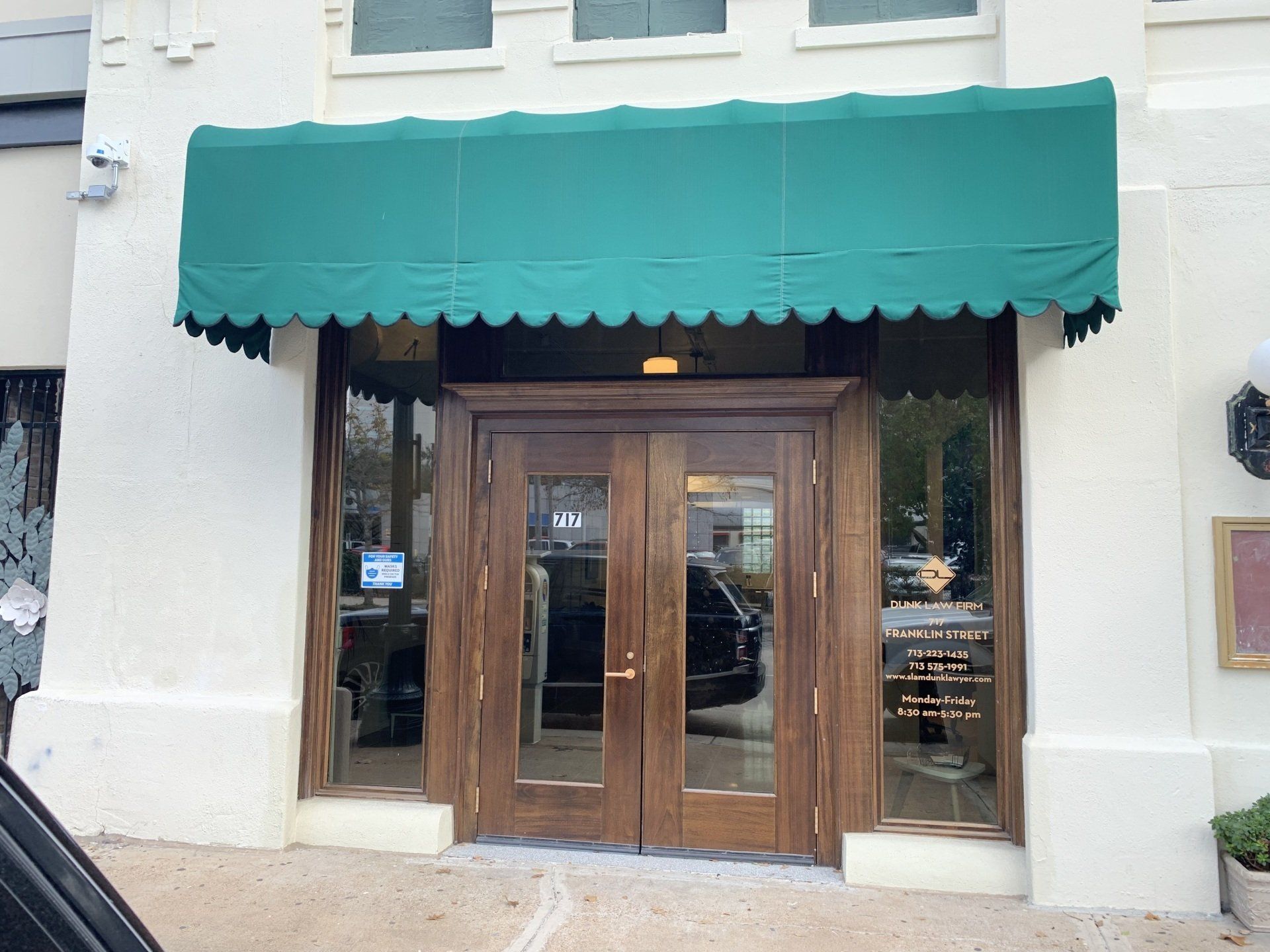Storefront entrance with green awning and wooden double doors