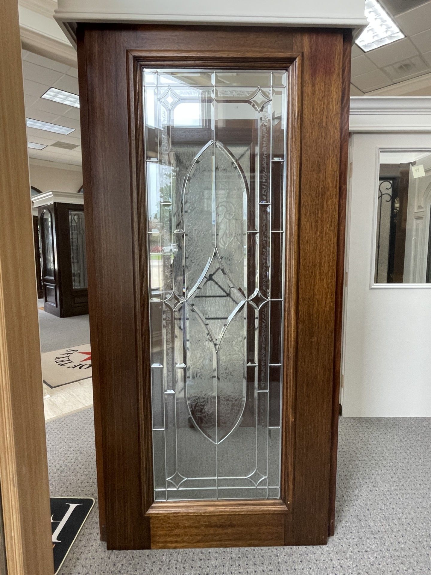 Wooden display cabinet with etched glass door in a showroom.