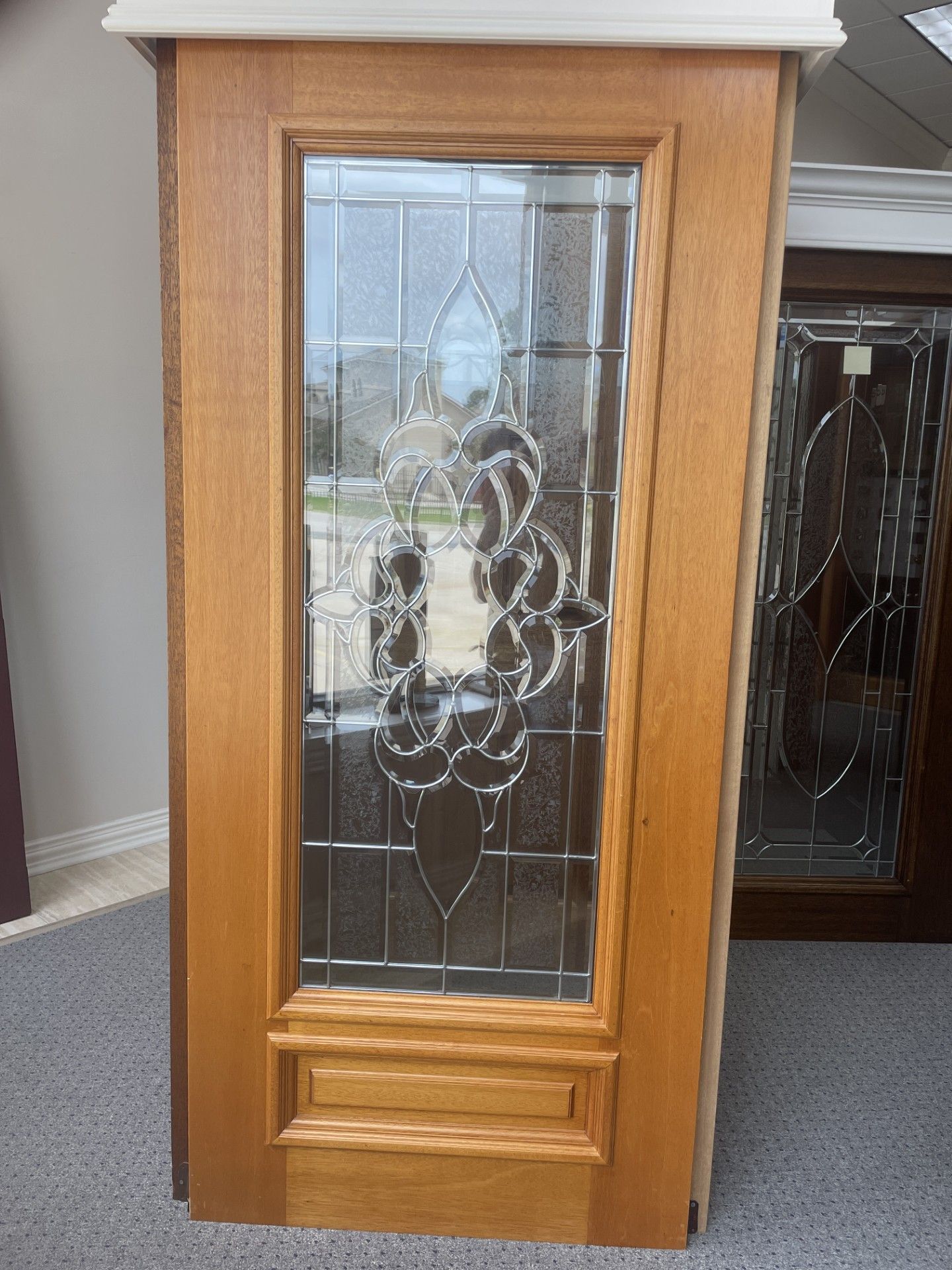 Wooden cabinet with a decorative beveled glass door on display in a showroom.