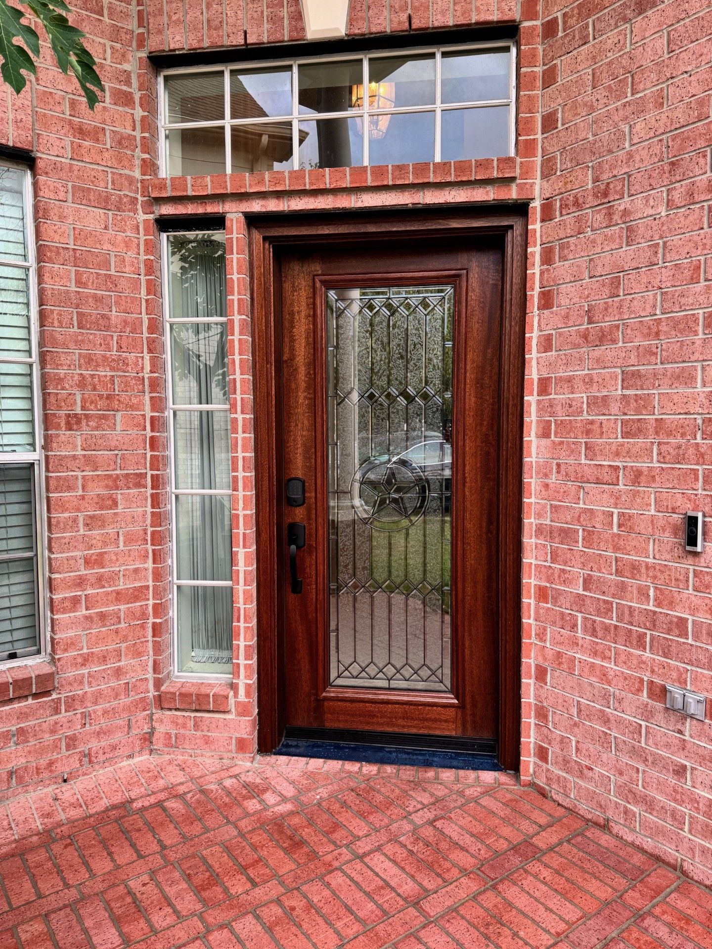 Red brick house entrance with a wooden and glass door and narrow side windows
