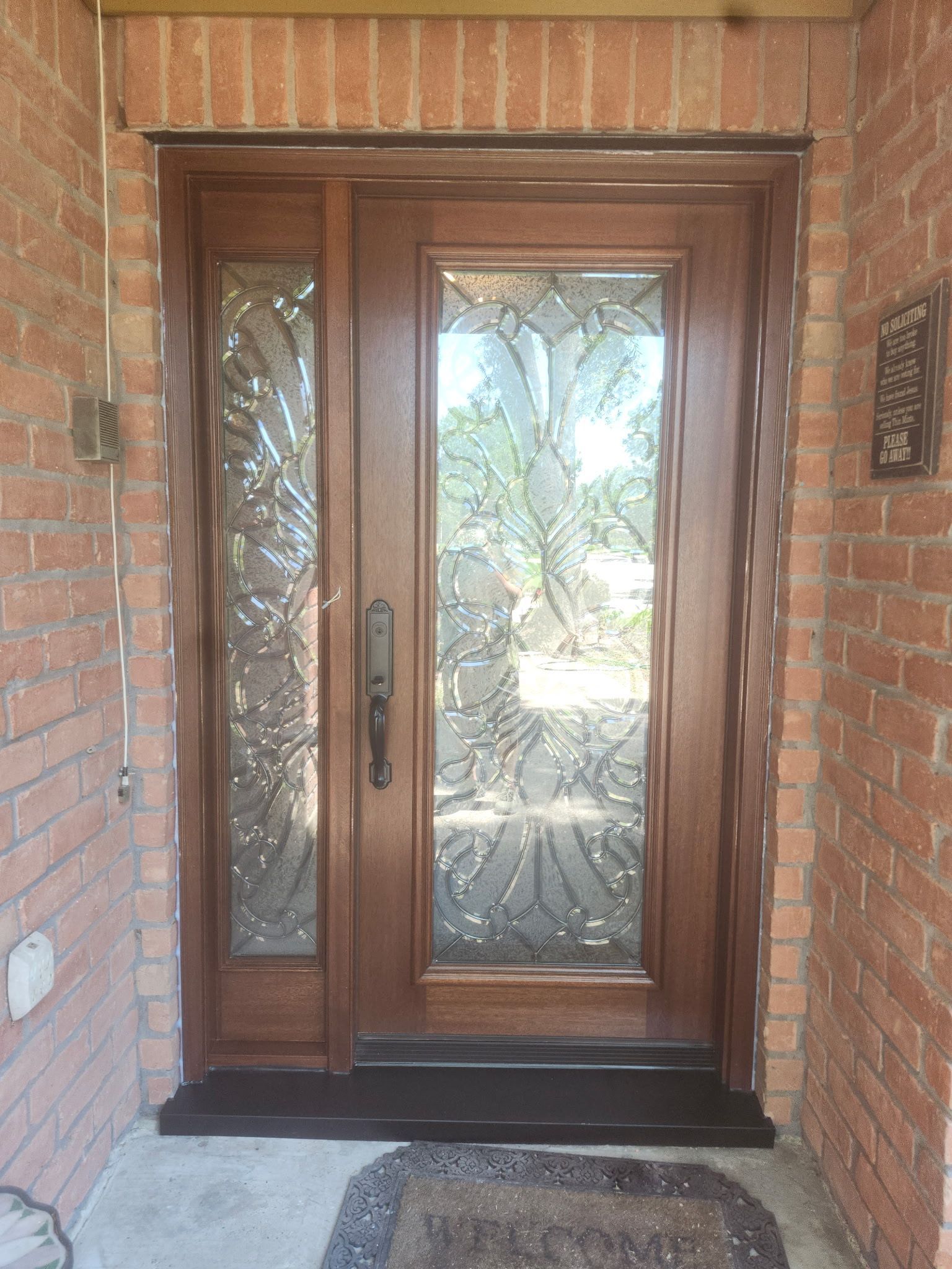 Wooden front door with glass panels set in a red brick entryway