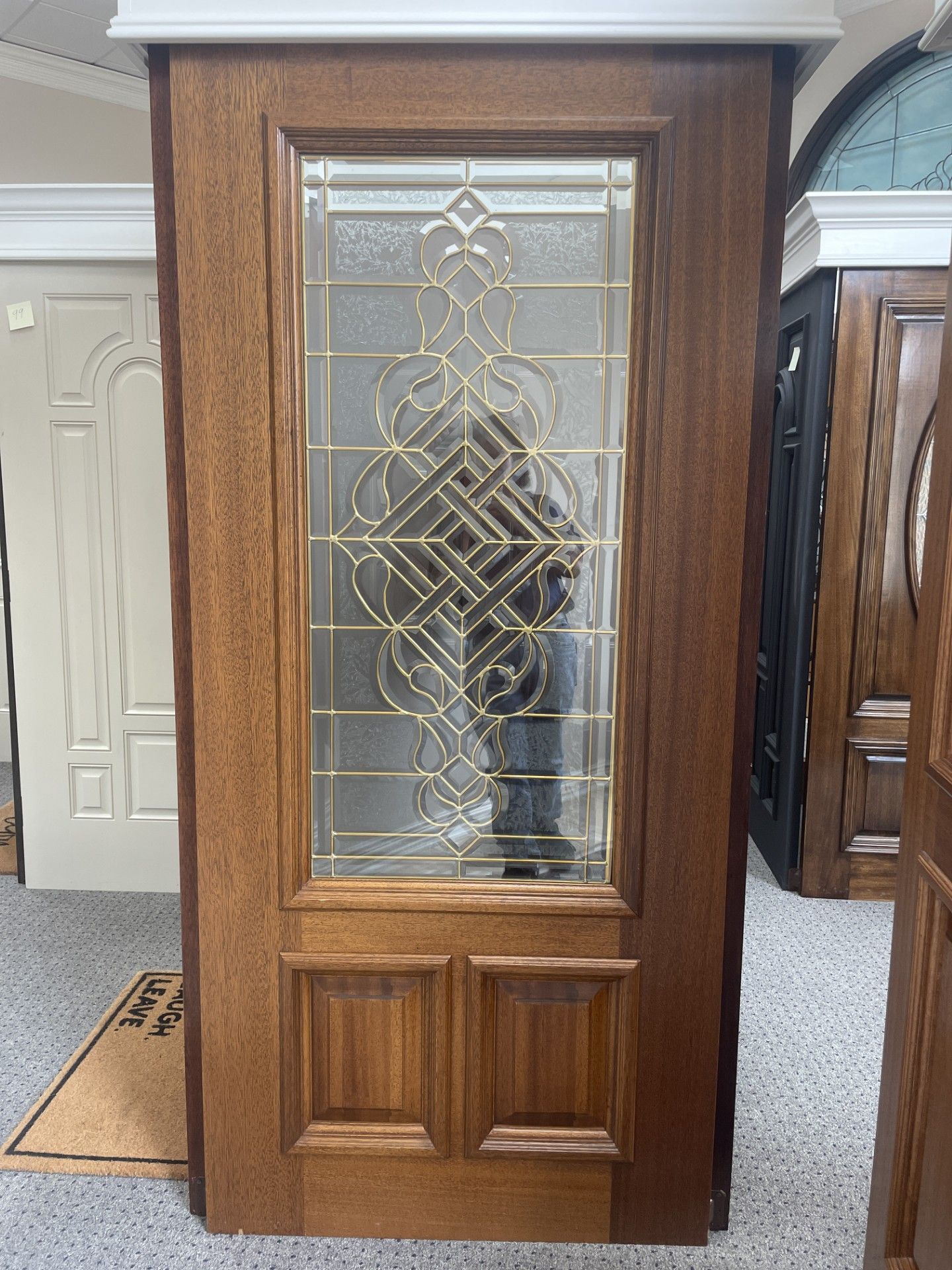 Wooden front door with decorative frosted glass panel in a showroom
