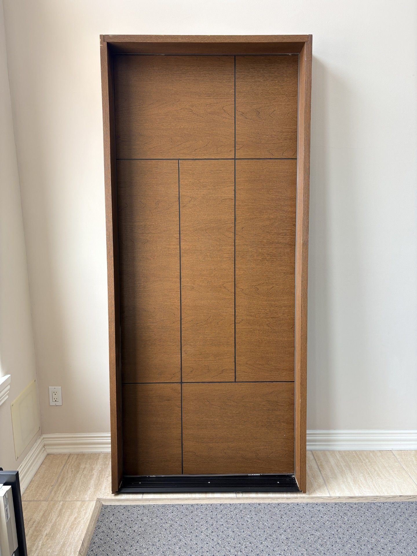 Empty wooden closet frame against a wall, with brown panel backing and a black base trim.