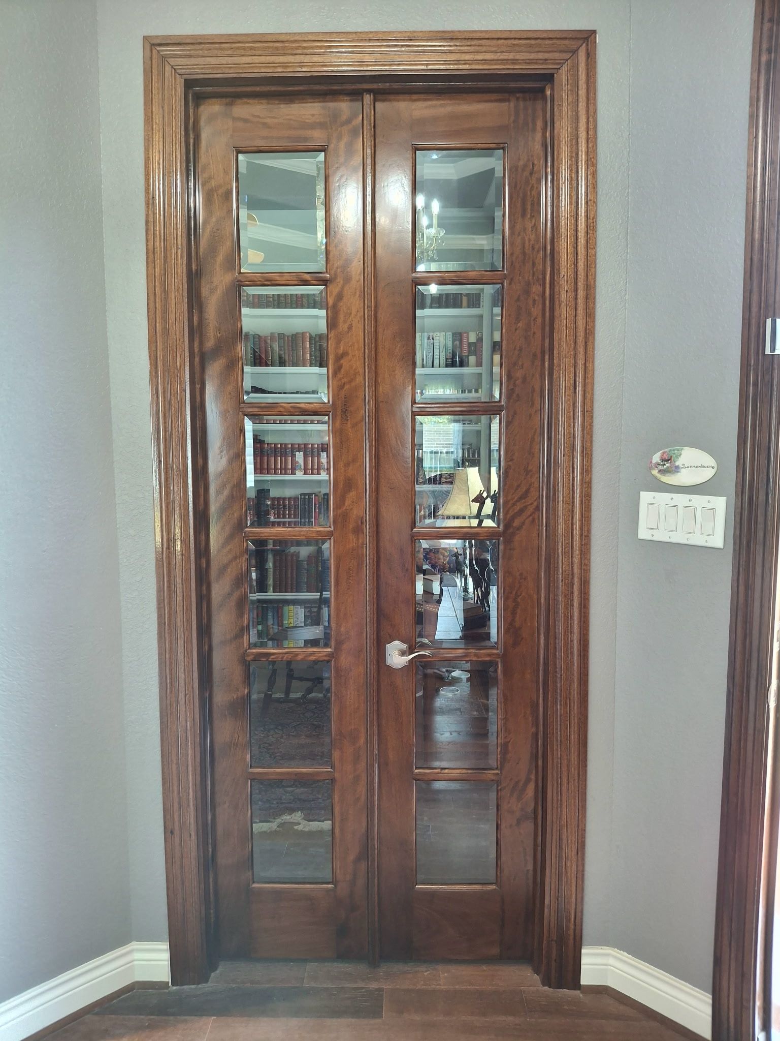 Wooden double glass doors with reflections in a gray-walled room