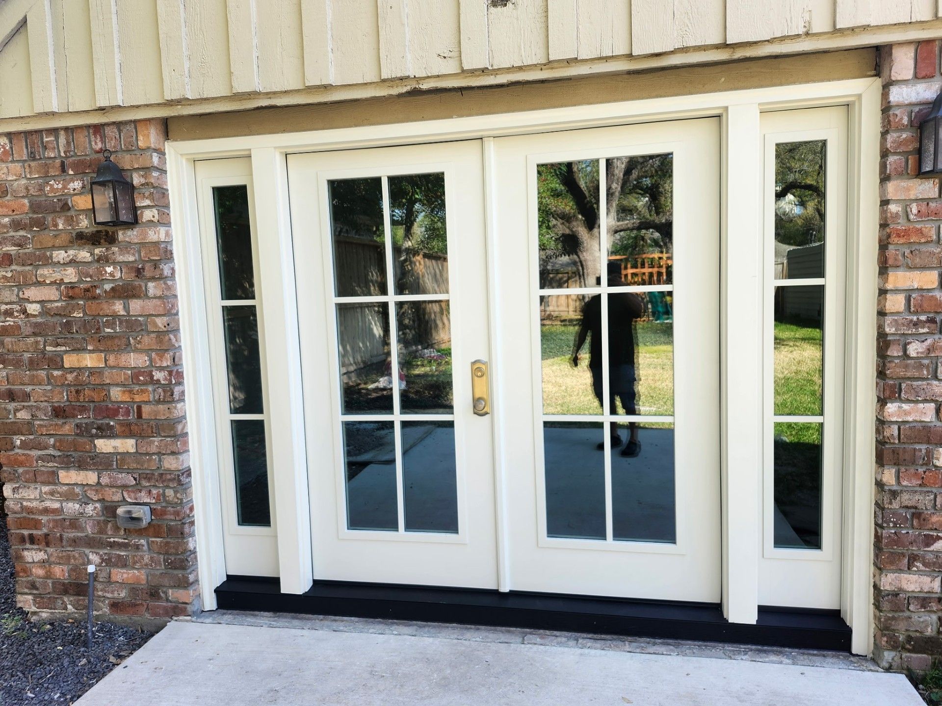 White French doors with glass panes on a brick house exterior