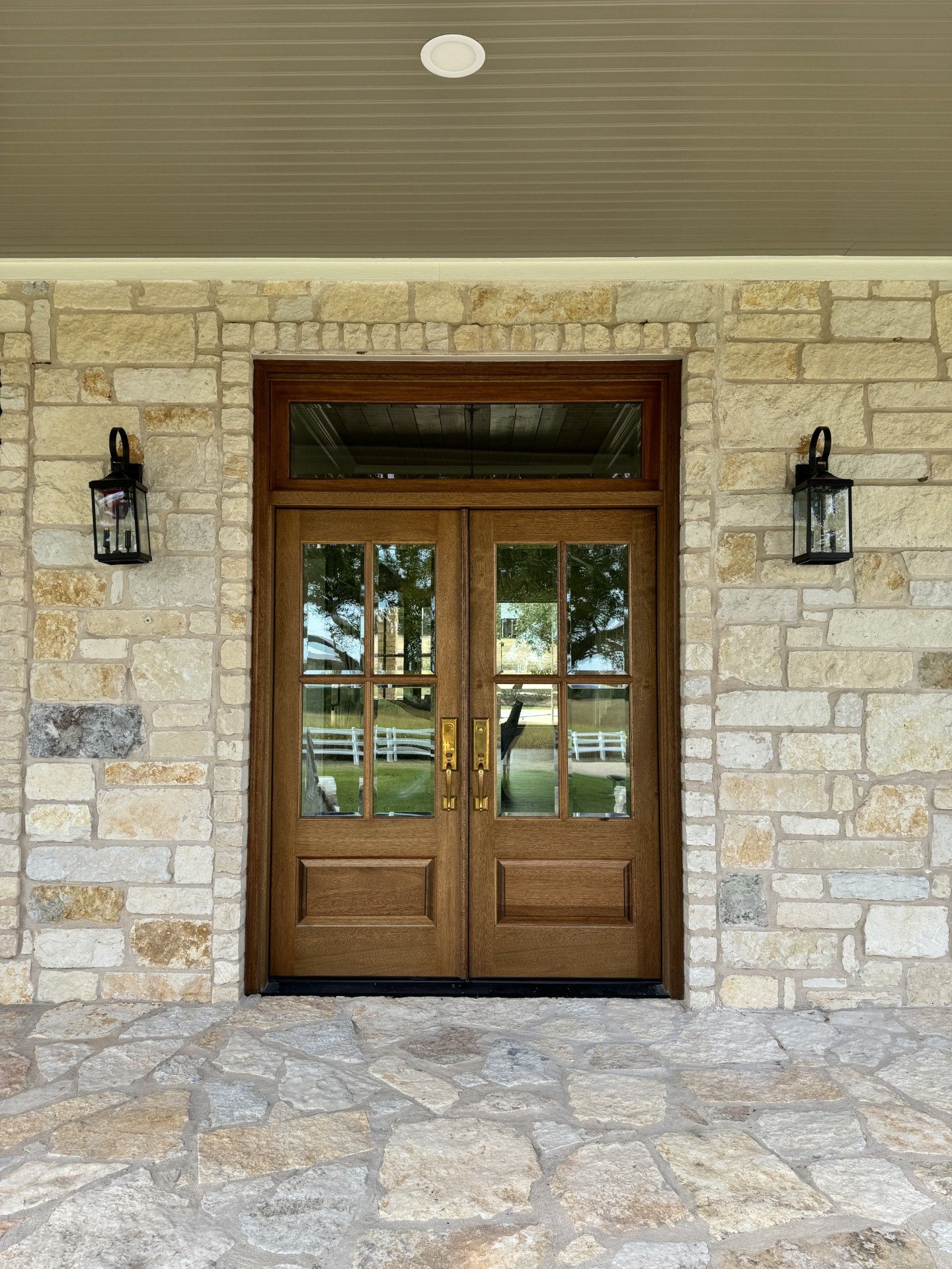 Stone entryway with wooden double doors and lanterns on either side