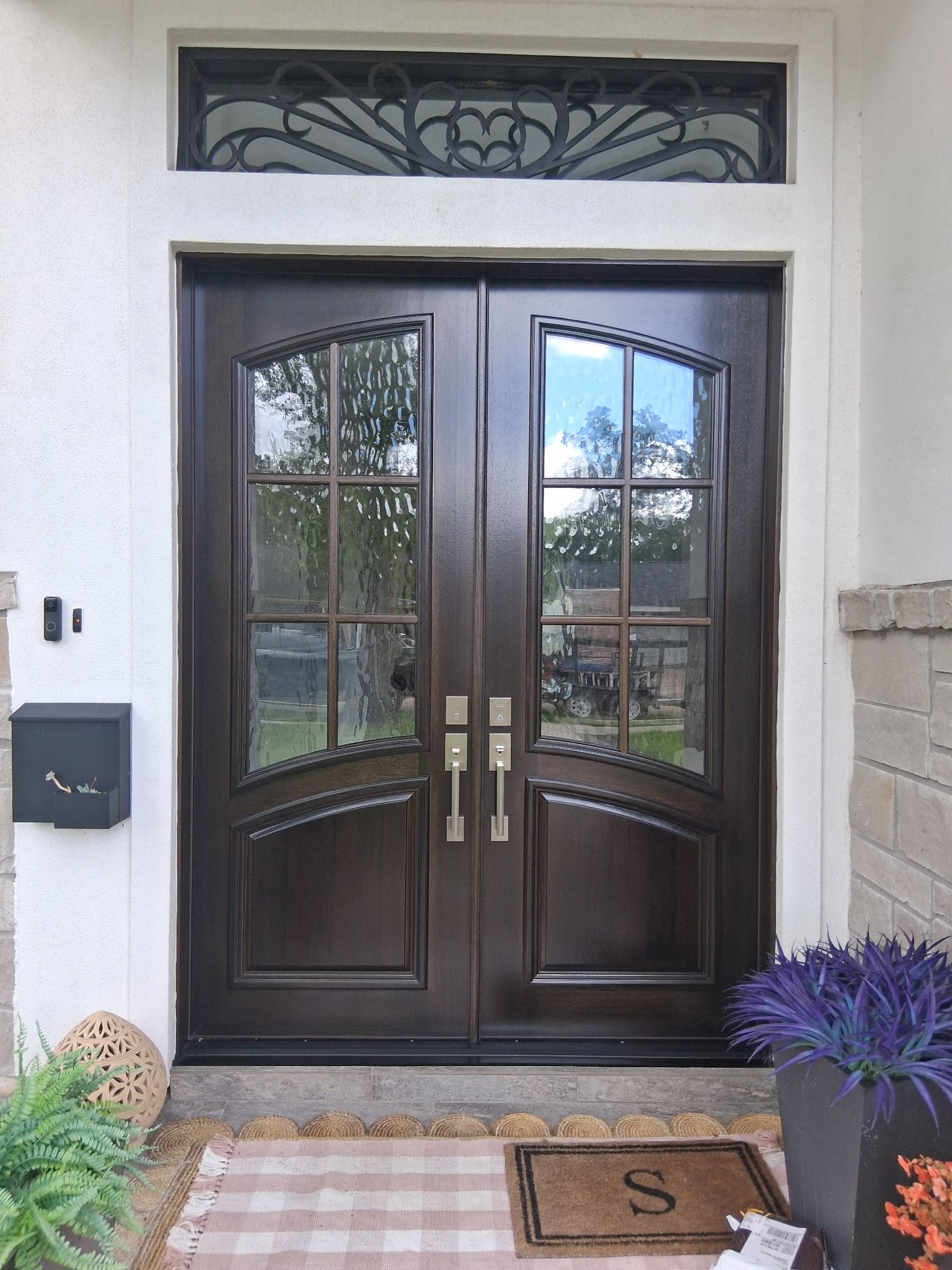 Dark double front doors with glass panes, framed by white trim and a small transom window above.