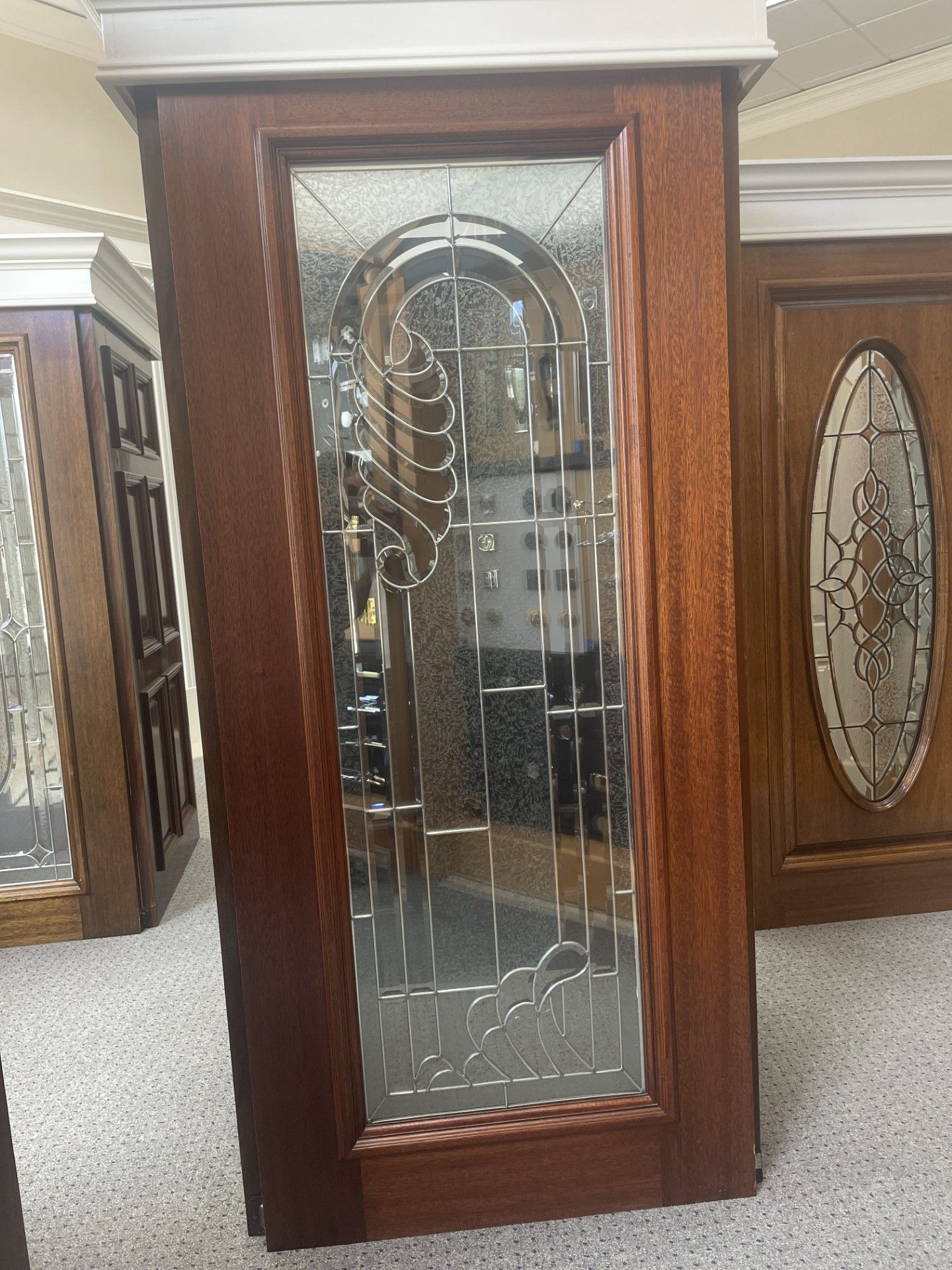 Wooden display cabinet with beveled glass door and mirrored interior, shown in a furniture showroom