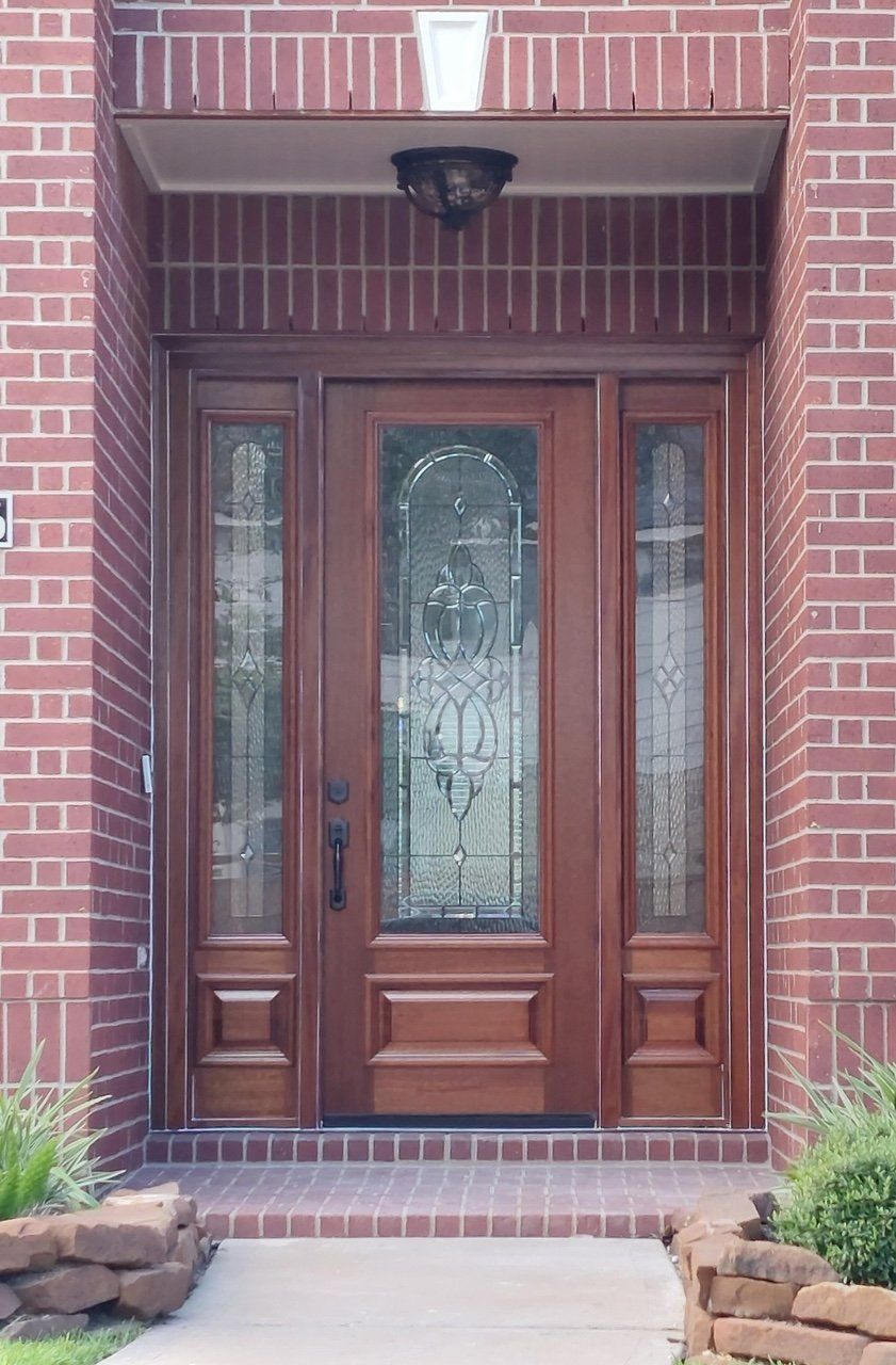 Wooden front door with glass panels set in a red brick entryway