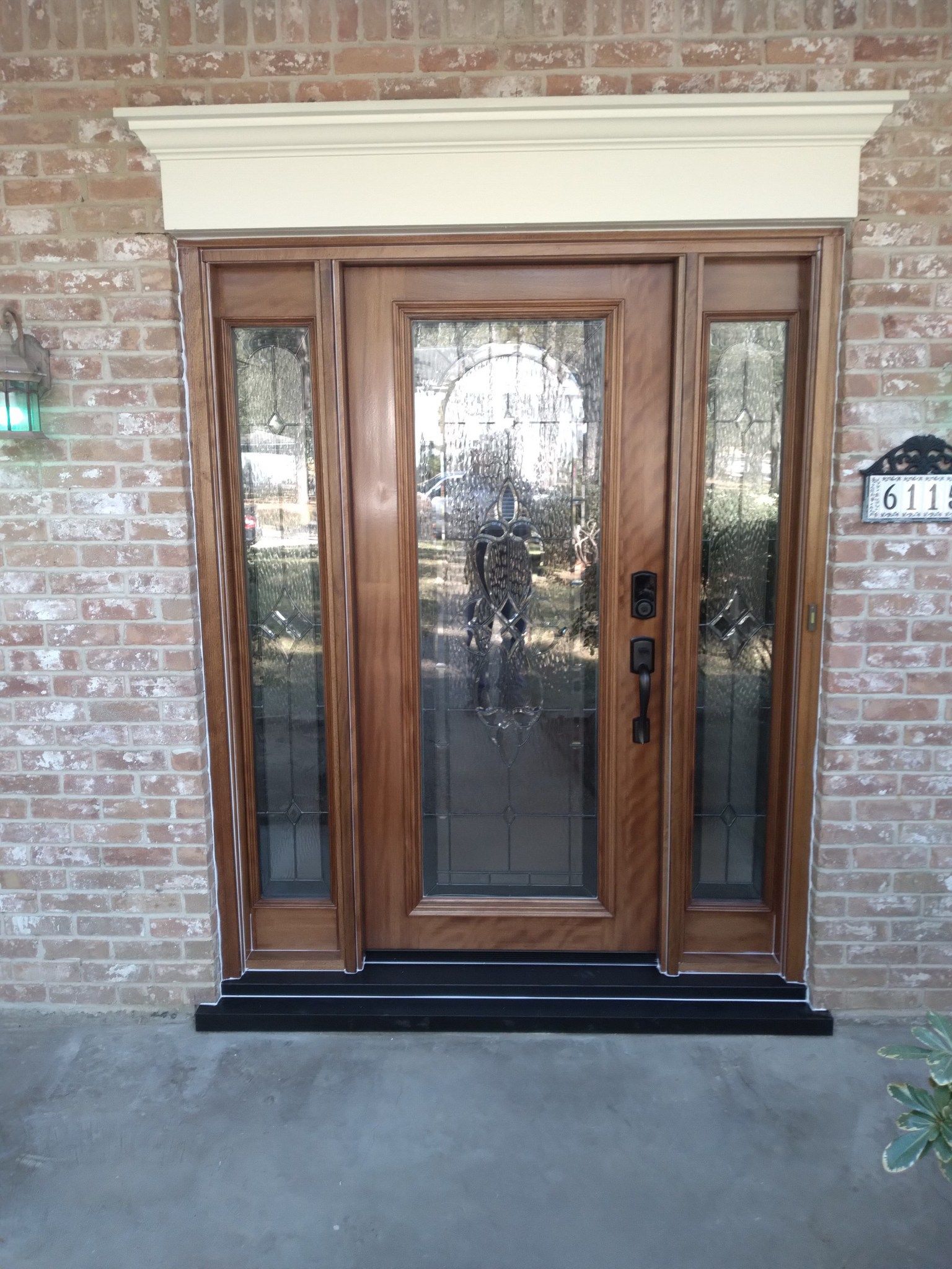 Wooden front door with glass panels in a brick exterior wall and cream trim