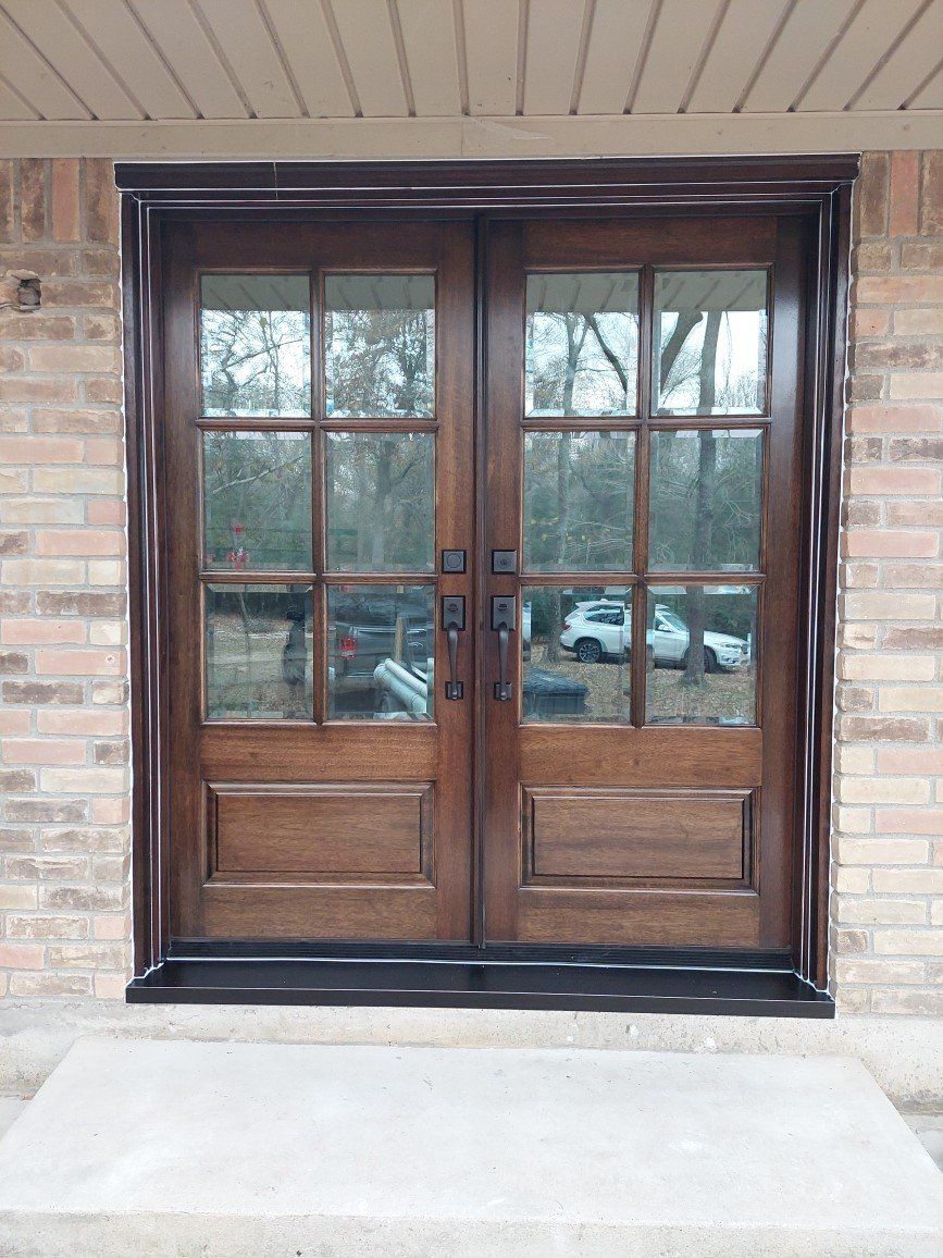 Wooden double front doors with glass panes set in a brick entryway