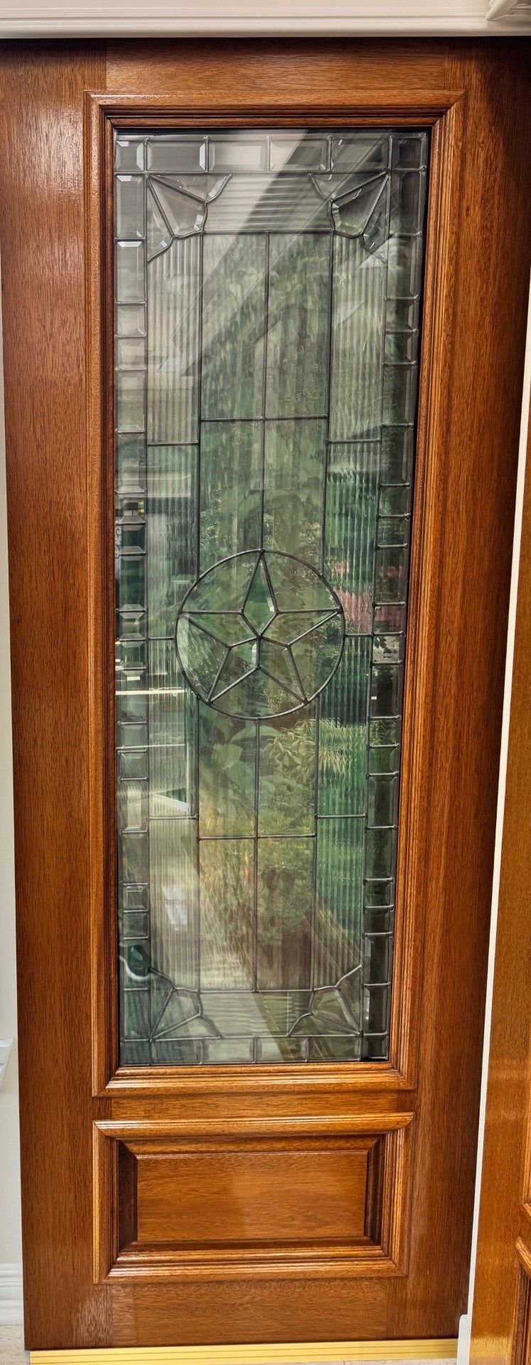 Wooden front door with a tall frosted glass panel and decorative etched design