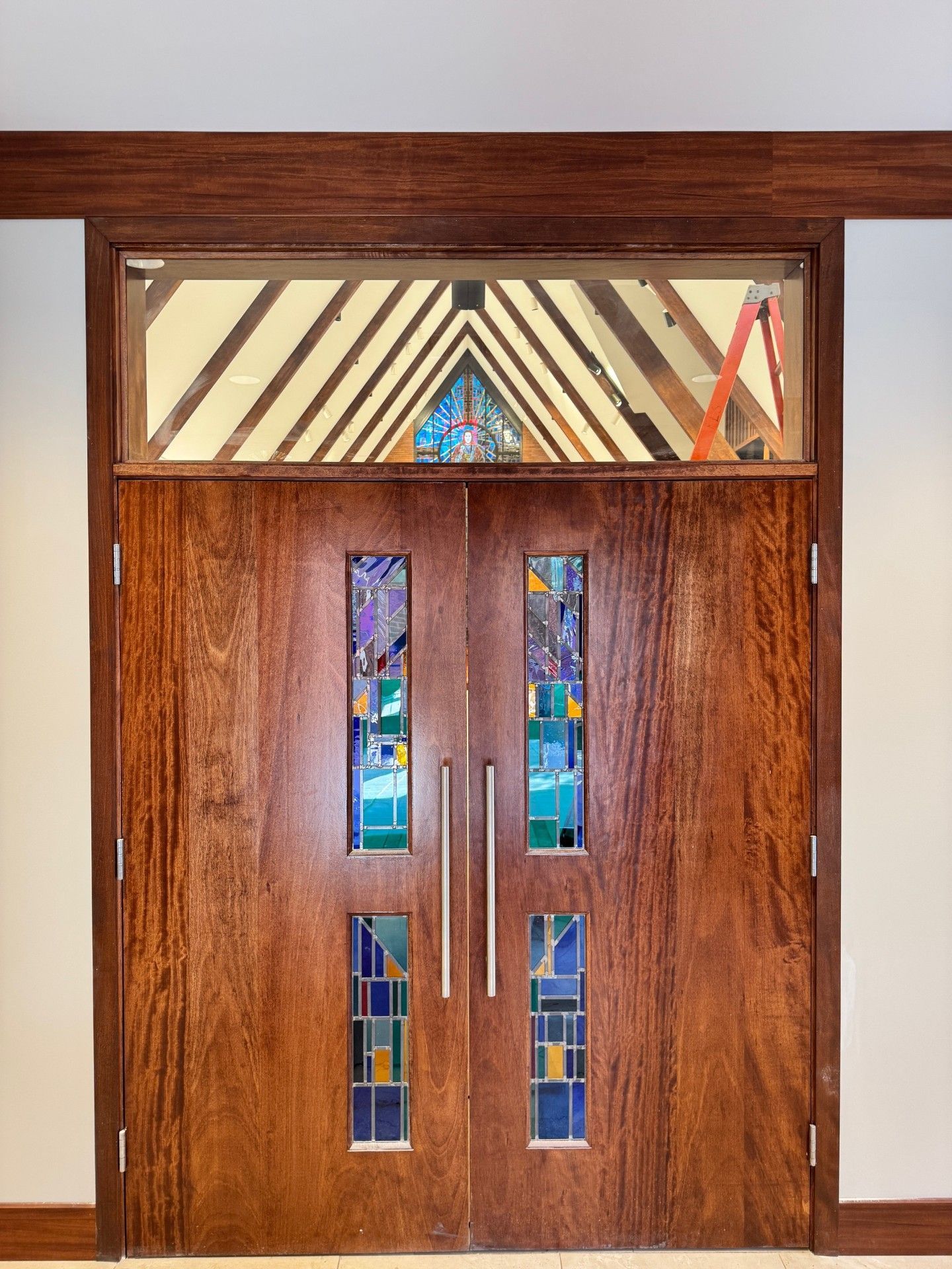Wooden double doors with stained-glass panels and a decorative transom above