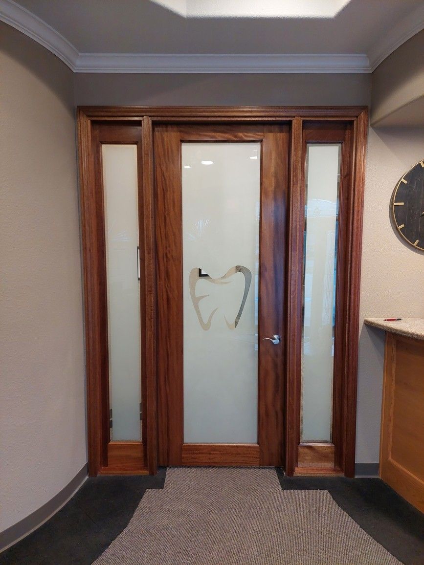 Wood-framed frosted glass double doors in a carpeted hallway with beige walls and a round wall clock