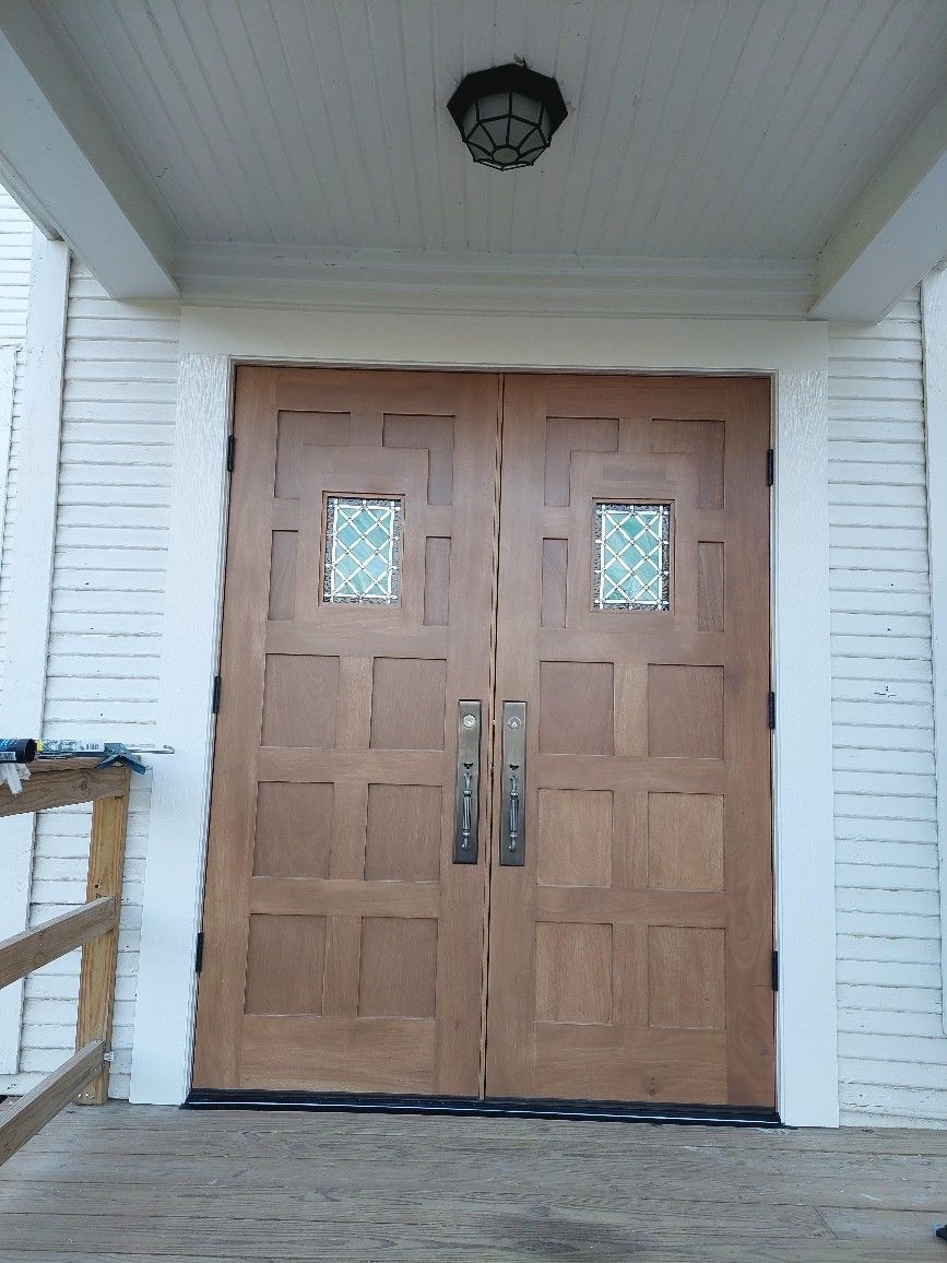 Double wooden front doors with frosted glass panes under a porch light