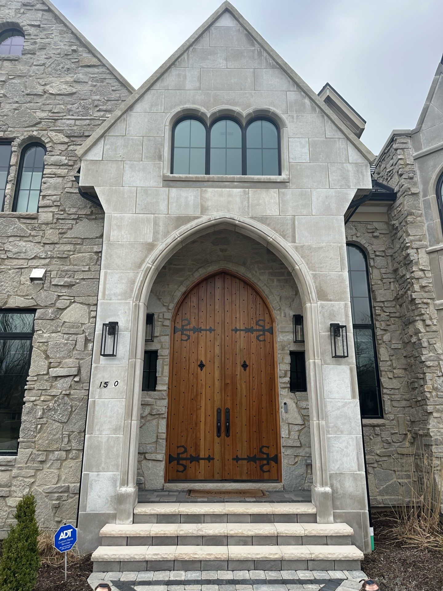 Stone church entrance with arched wooden double doors and steps leading up to it