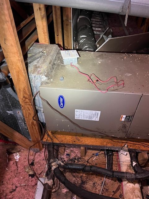Attic HVAC unit with exposed red wires, insulation, and wooden framing around it