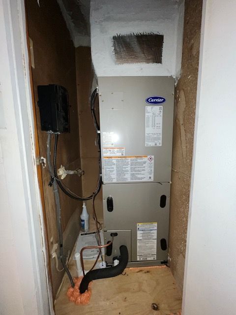HVAC furnace in a small utility closet with exposed wiring and ductwork at the bottom.