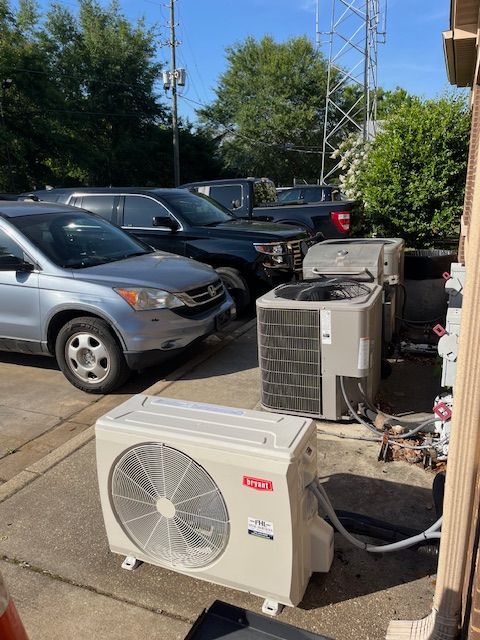 Outdoor parking lot with parked cars and two HVAC units on the ground near a building.