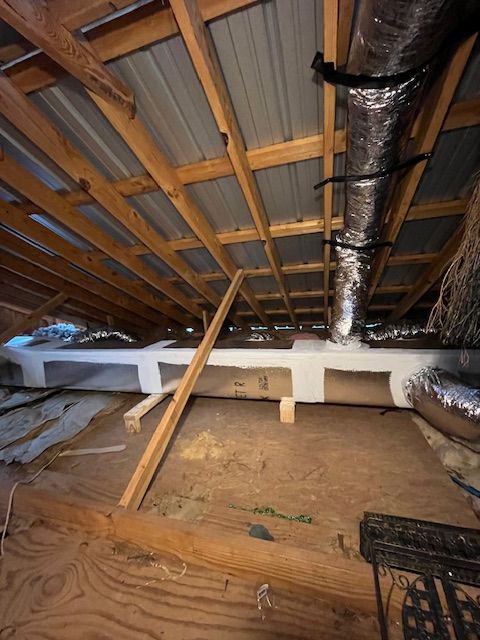 Attic crawlspace with exposed beams, insulation, ductwork, and a wooden floor opening.