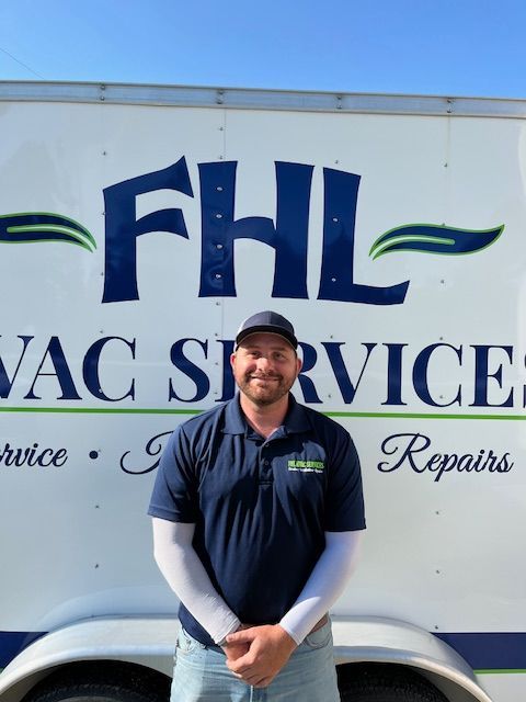 Man standing in front of an FHL HVAC Services truck, wearing a navy shirt and cap.