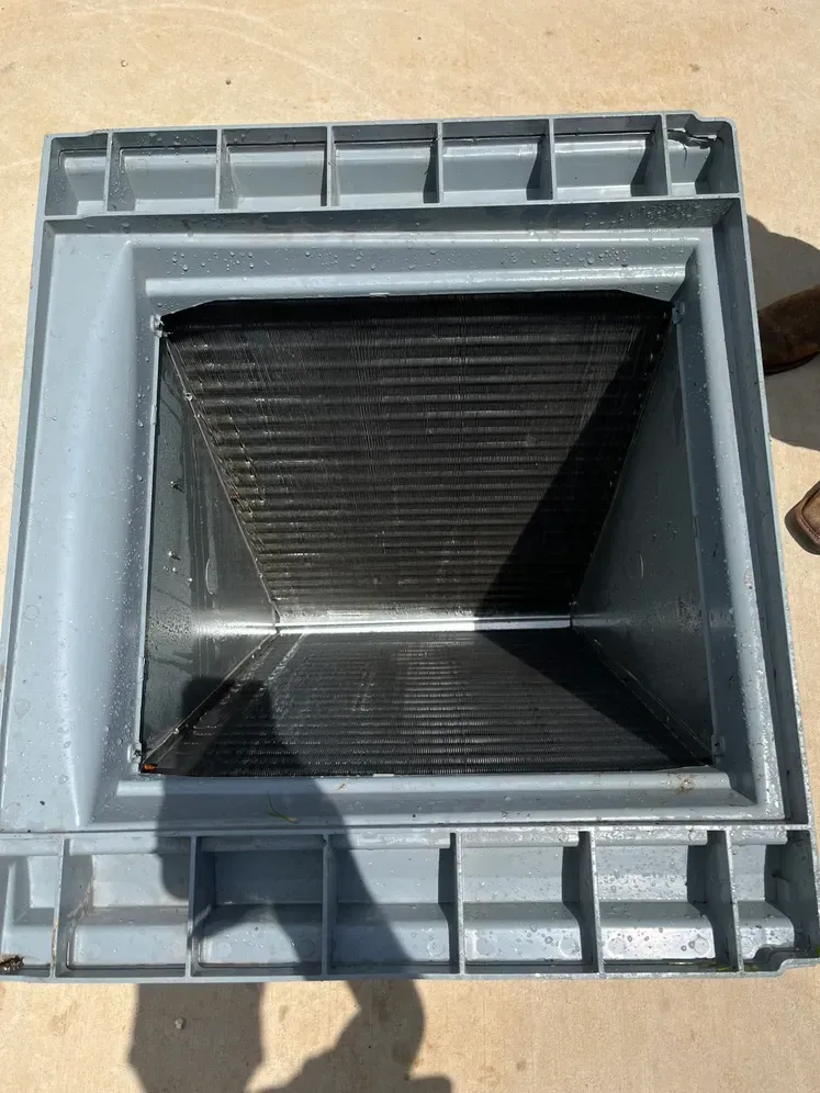 Square black ventilation shaft in a gray frame on a tan surface, viewed from above.
