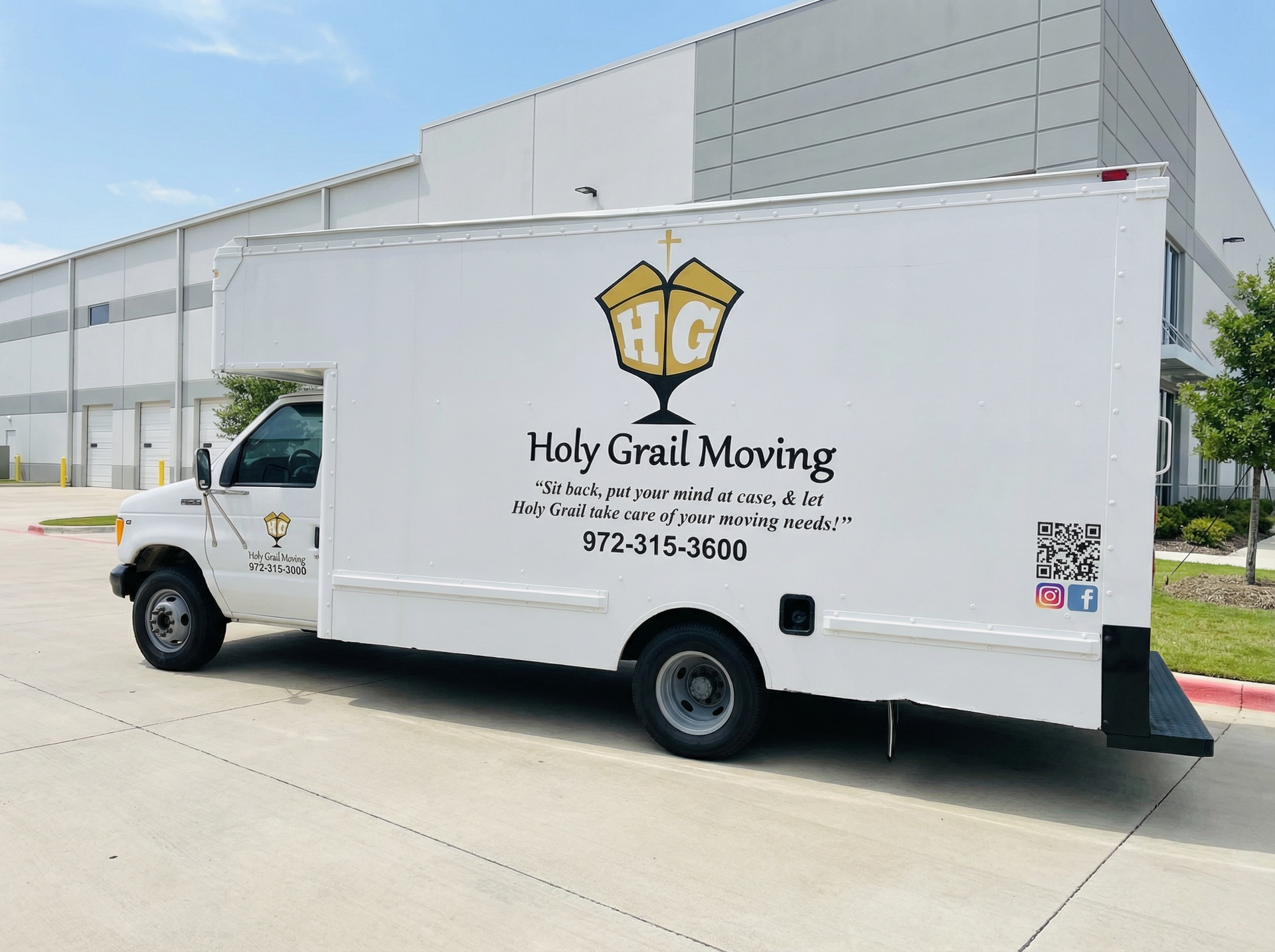 White Hoyt’s Moving truck parked outside a warehouse on a sunny day.