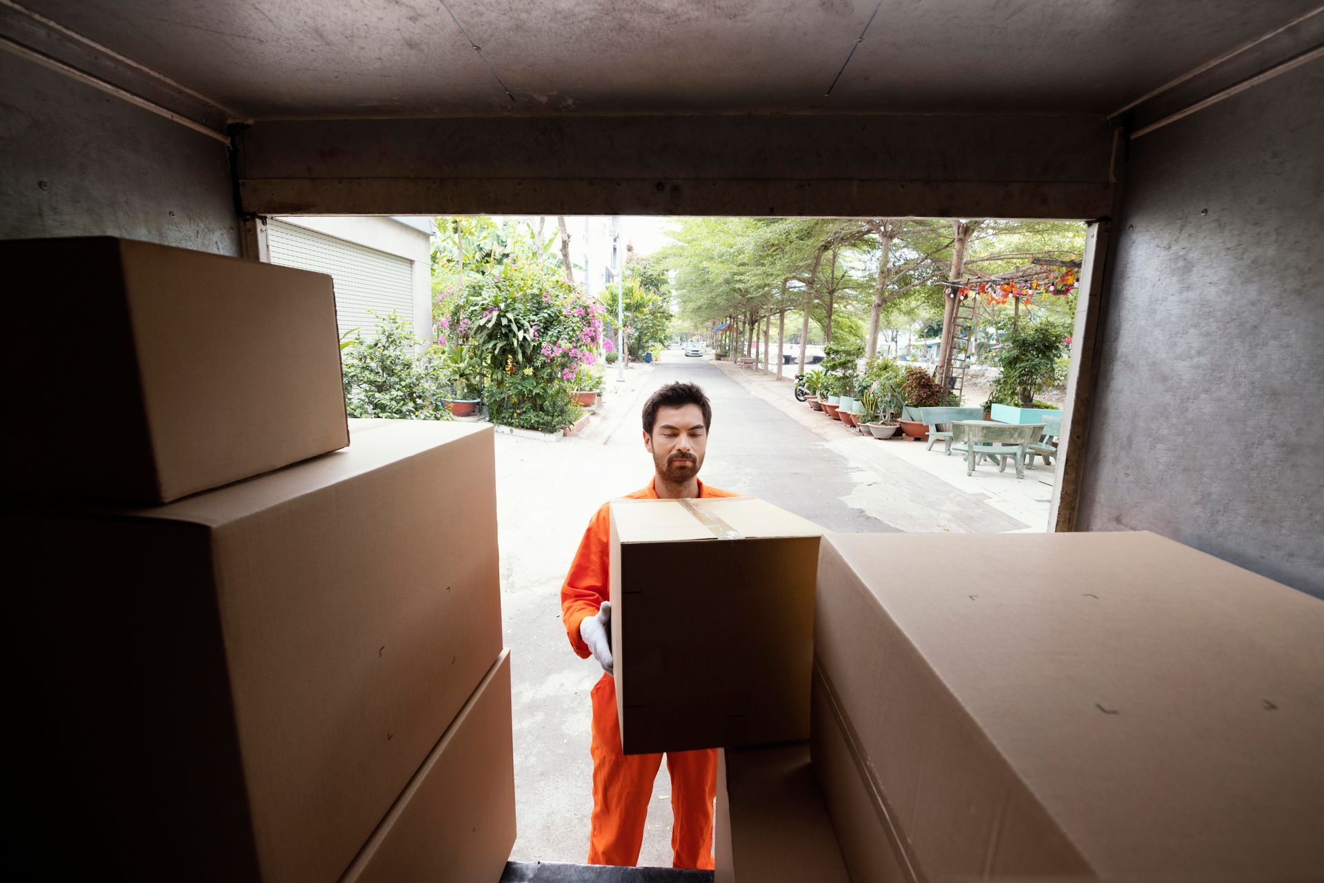 Person carrying a box from the back of a truck lined with moving boxes