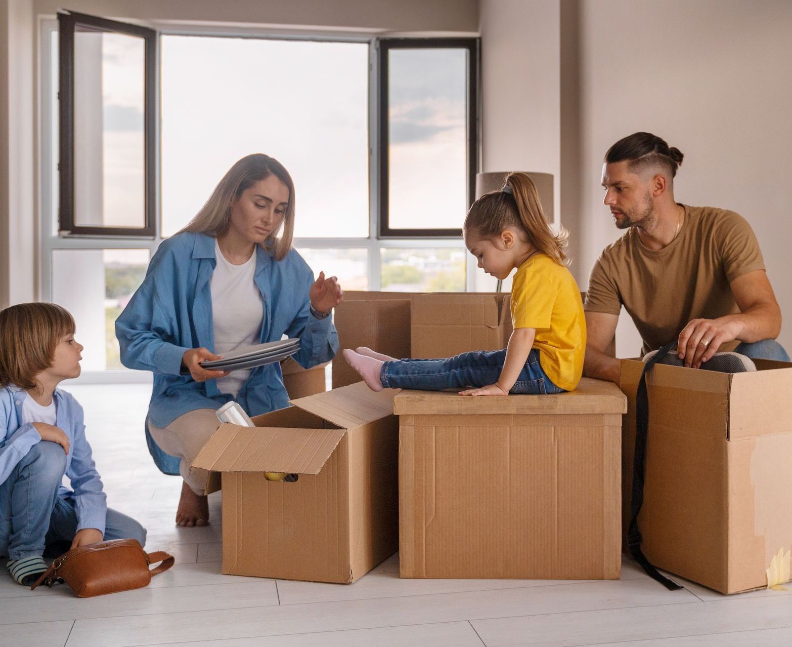 Family unpacking cardboard boxes in a bright room with open windows
