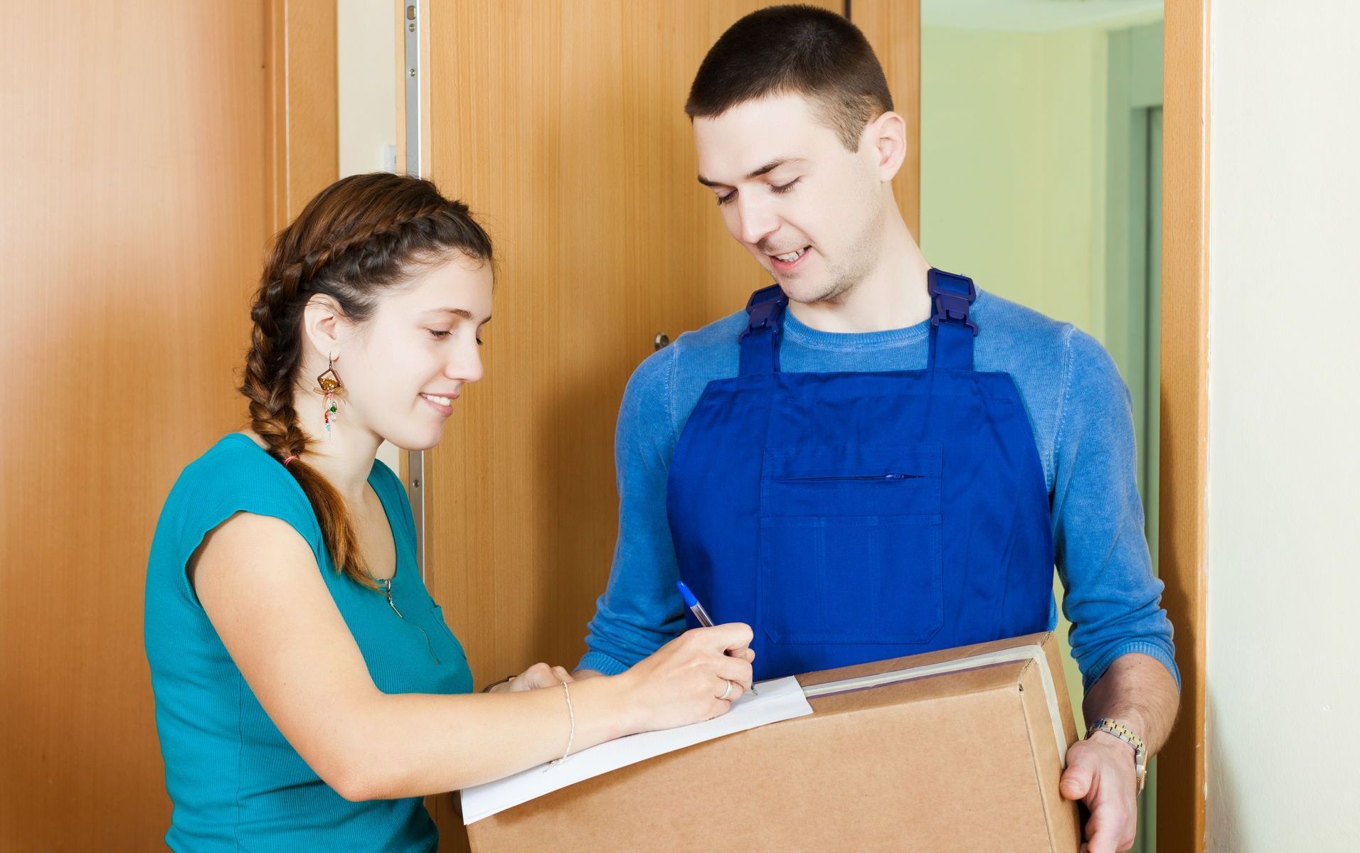 Two people in an entryway checking a clipboard together, one holding a box