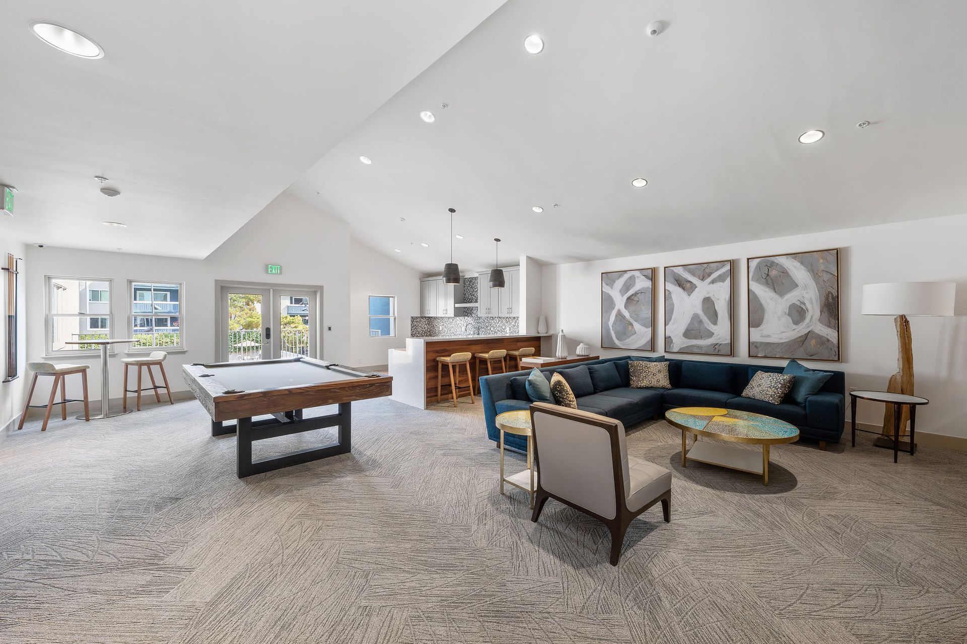Spacious community lounge with a pool table, bar seating, and modern seating area at Ballena Village apartments in Alameda, CA.