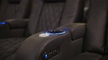 A close up of a movie theater seat with a cup holder.