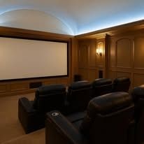 A home theater with a large screen and black leather seats.