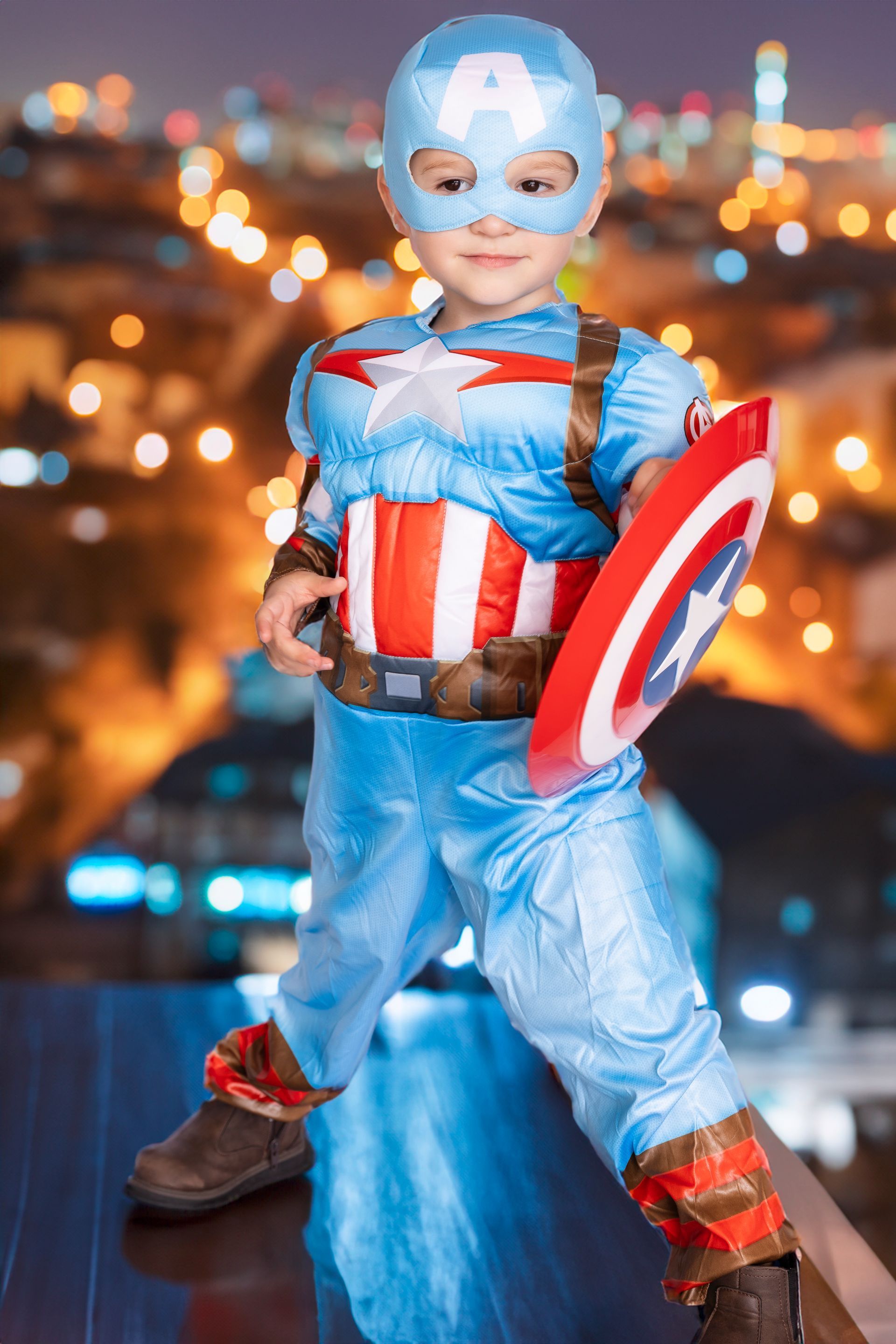 A little boy in a captain america costume is holding a shield.