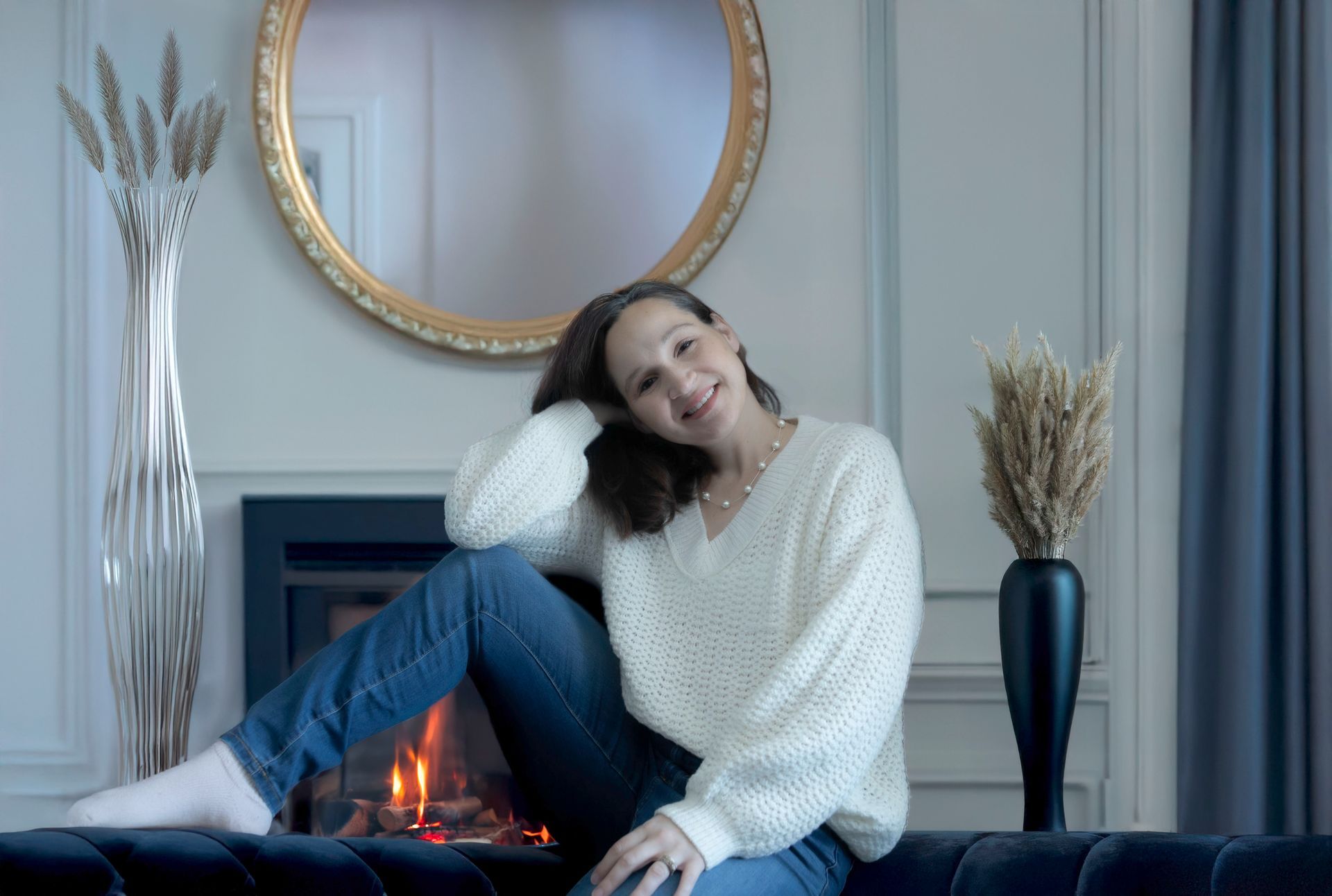 A woman is sitting on a couch in front of a fireplace.